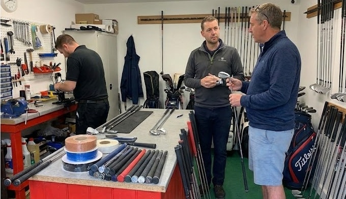 People discussing golf clubs in workshop