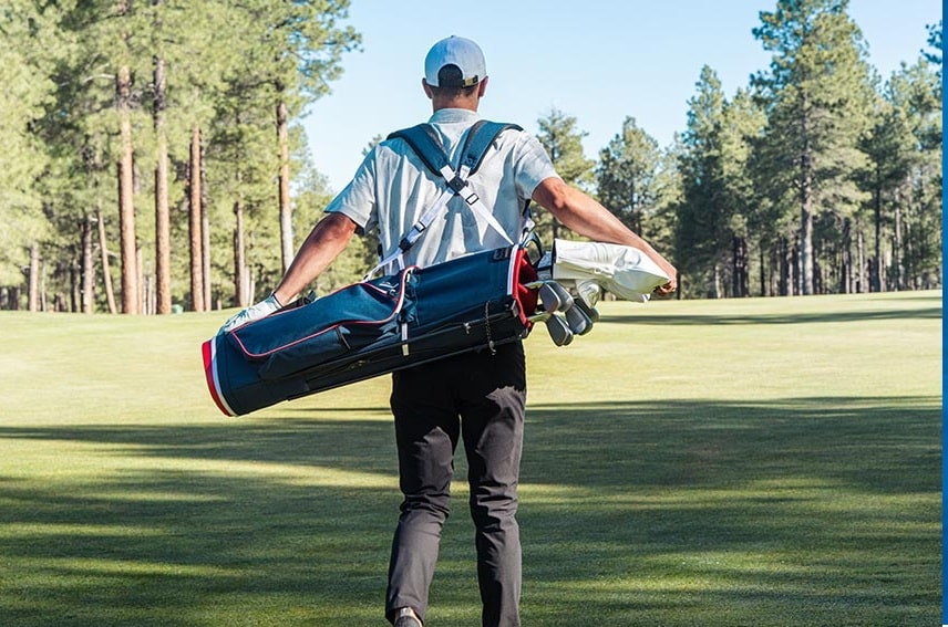 Golfer carrying bag on sunny golf course