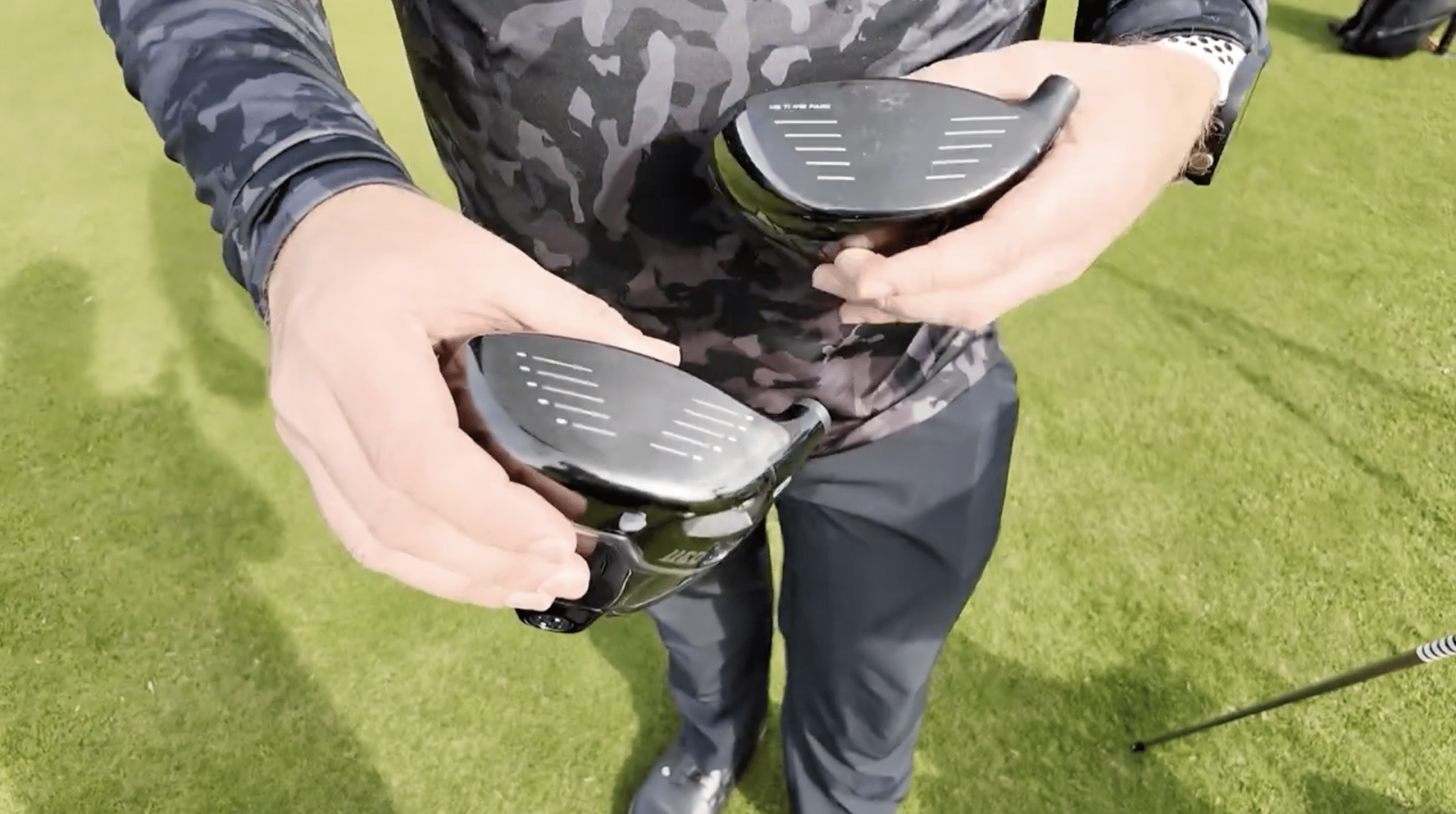 Person holding two golf club drivers outdoors