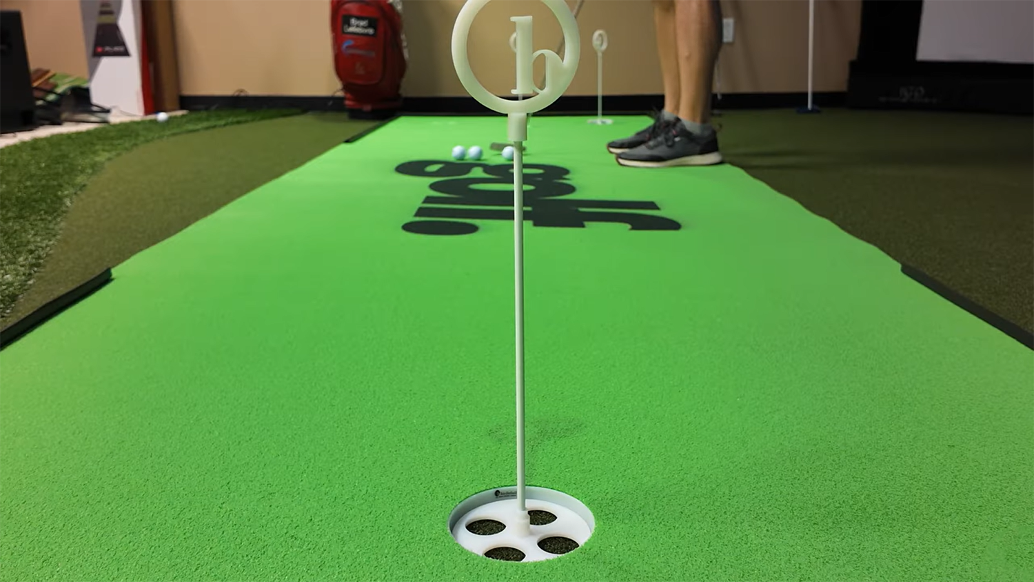 Indoor putting green with flagstick, cup, and golf balls