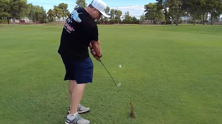 Golfer in action swinging club on green grass.