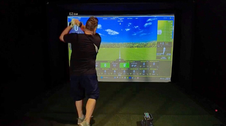 Person golfing indoors with a simulation screen