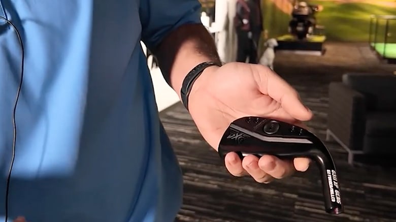 Person holding a golf club in a demonstration.