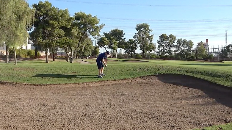 Golfer preparing to hit from a sand bunker.