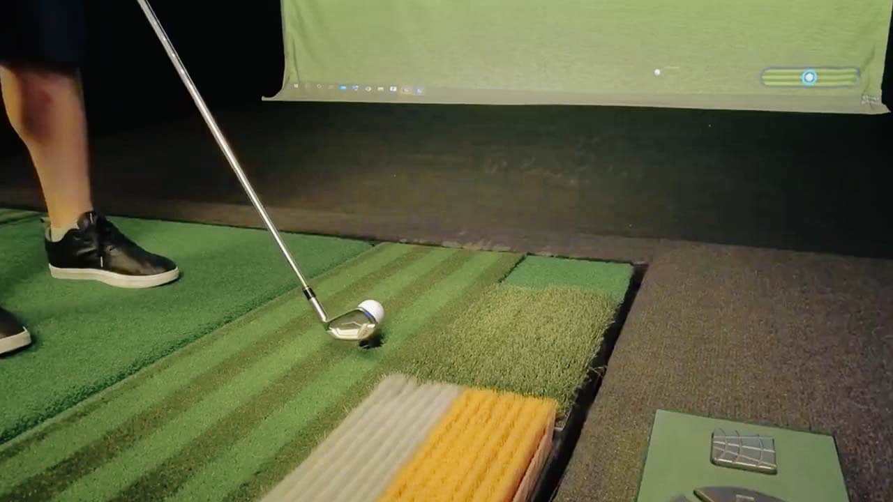 Person practicing golf swing on artificial grass.