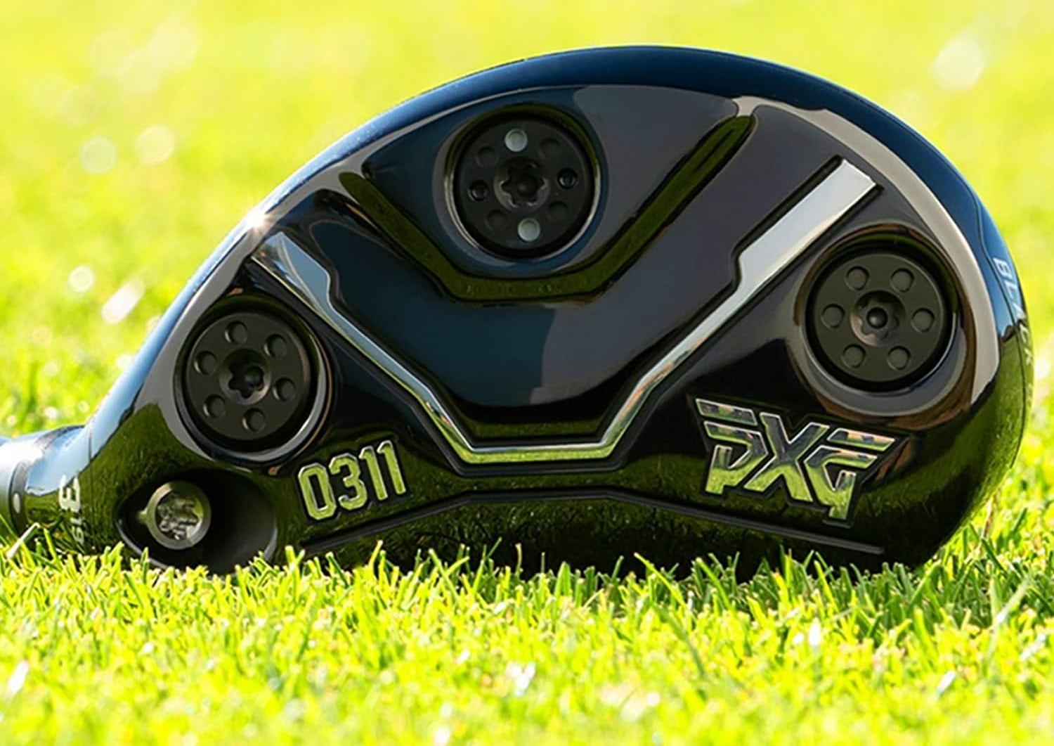 Close-up of a PXG golf club head on grass.