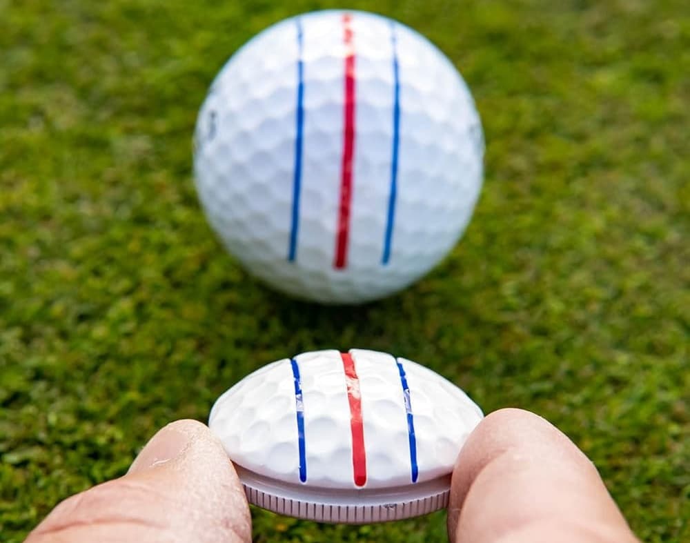 Hand holding golf tee near golf ball.