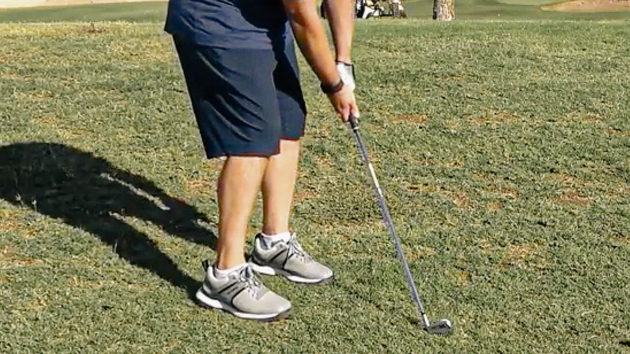 Person preparing to swing a golf club.