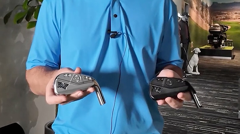 Person holding two golf clubs in each hand.