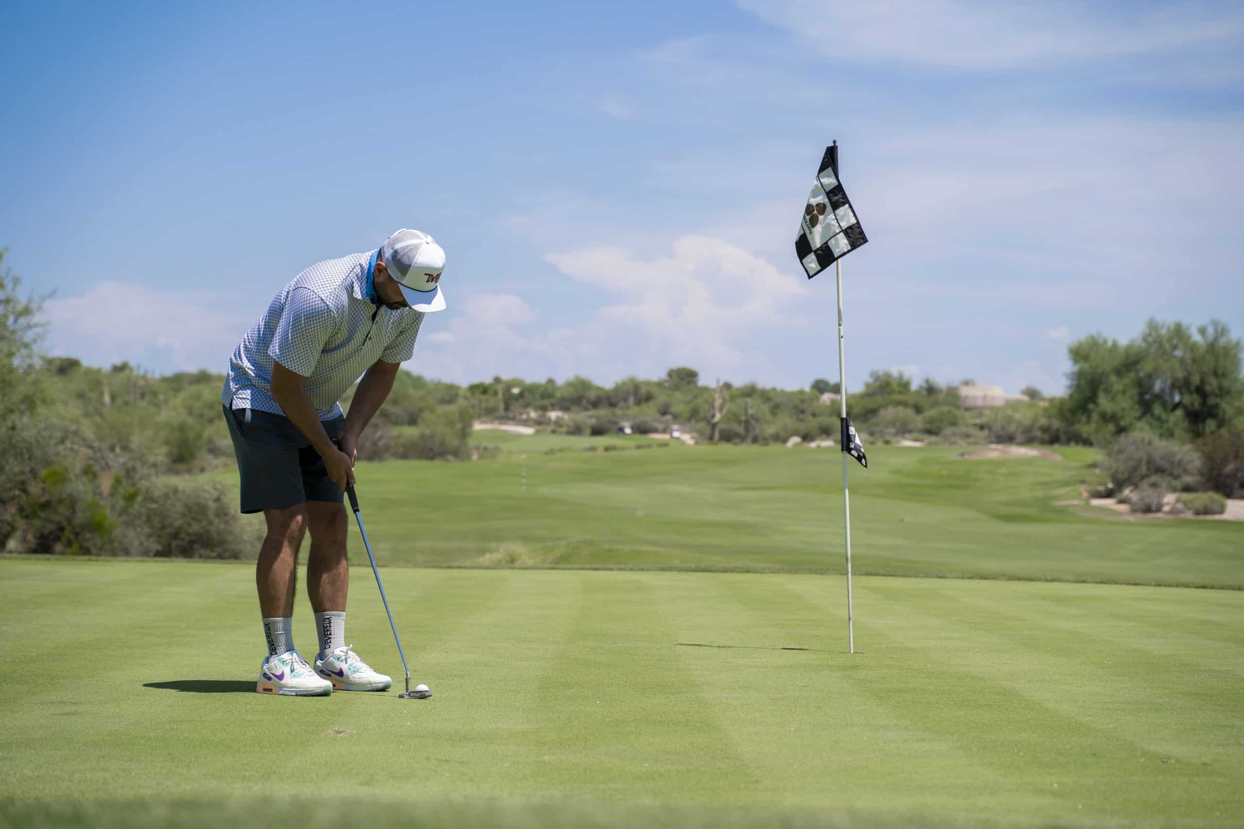 Golfer putting on a sunny green golf course.