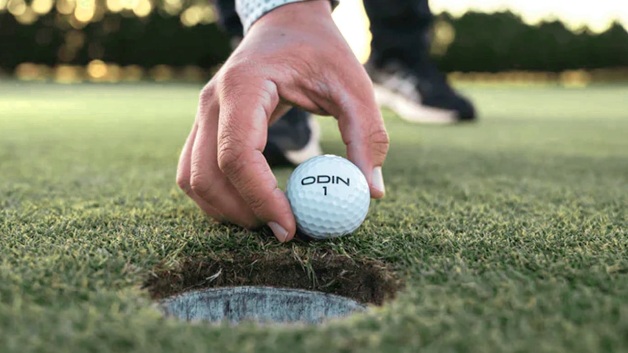 Hand placing golf ball near the hole