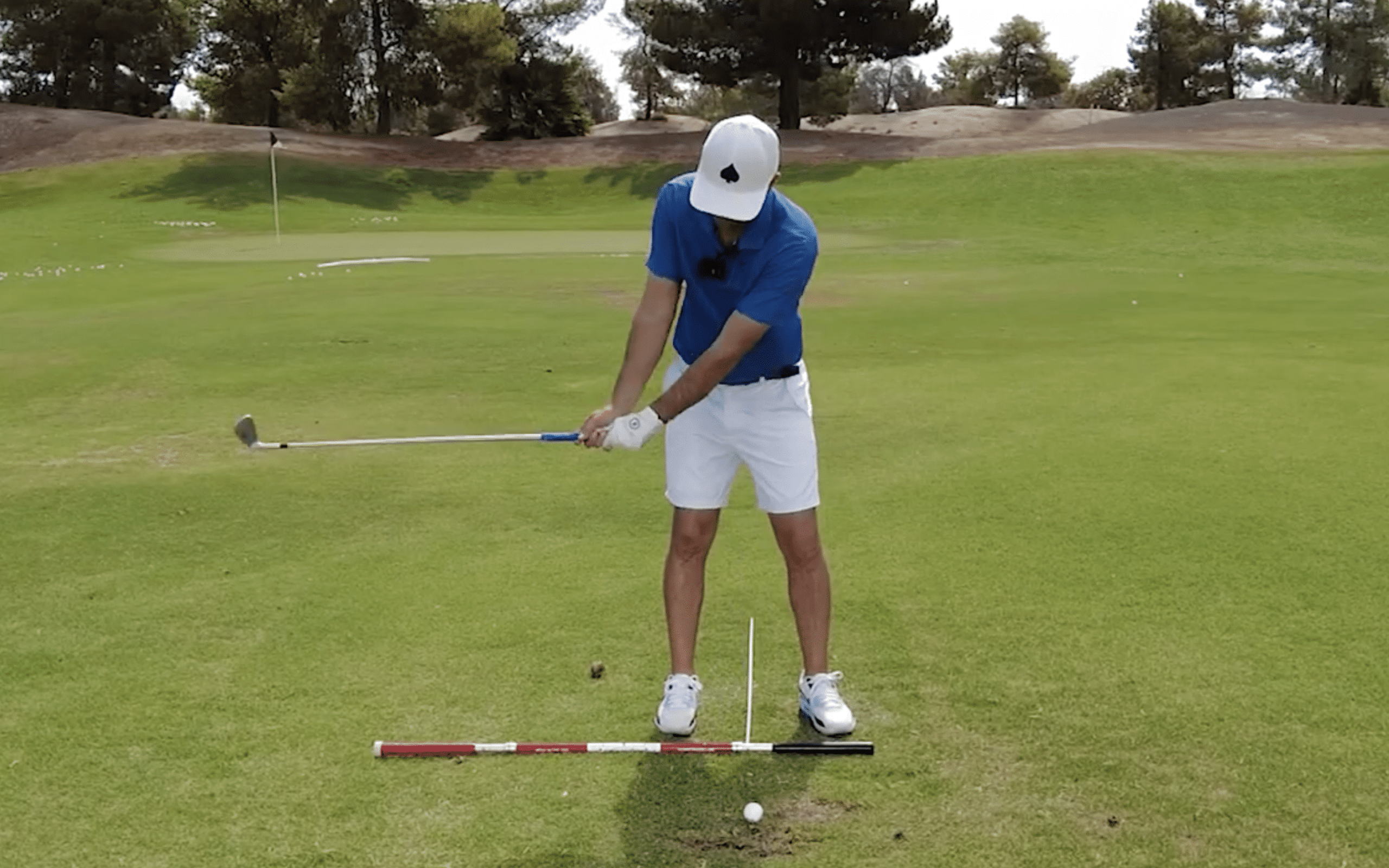 Golfer practicing swing with alignment aids.