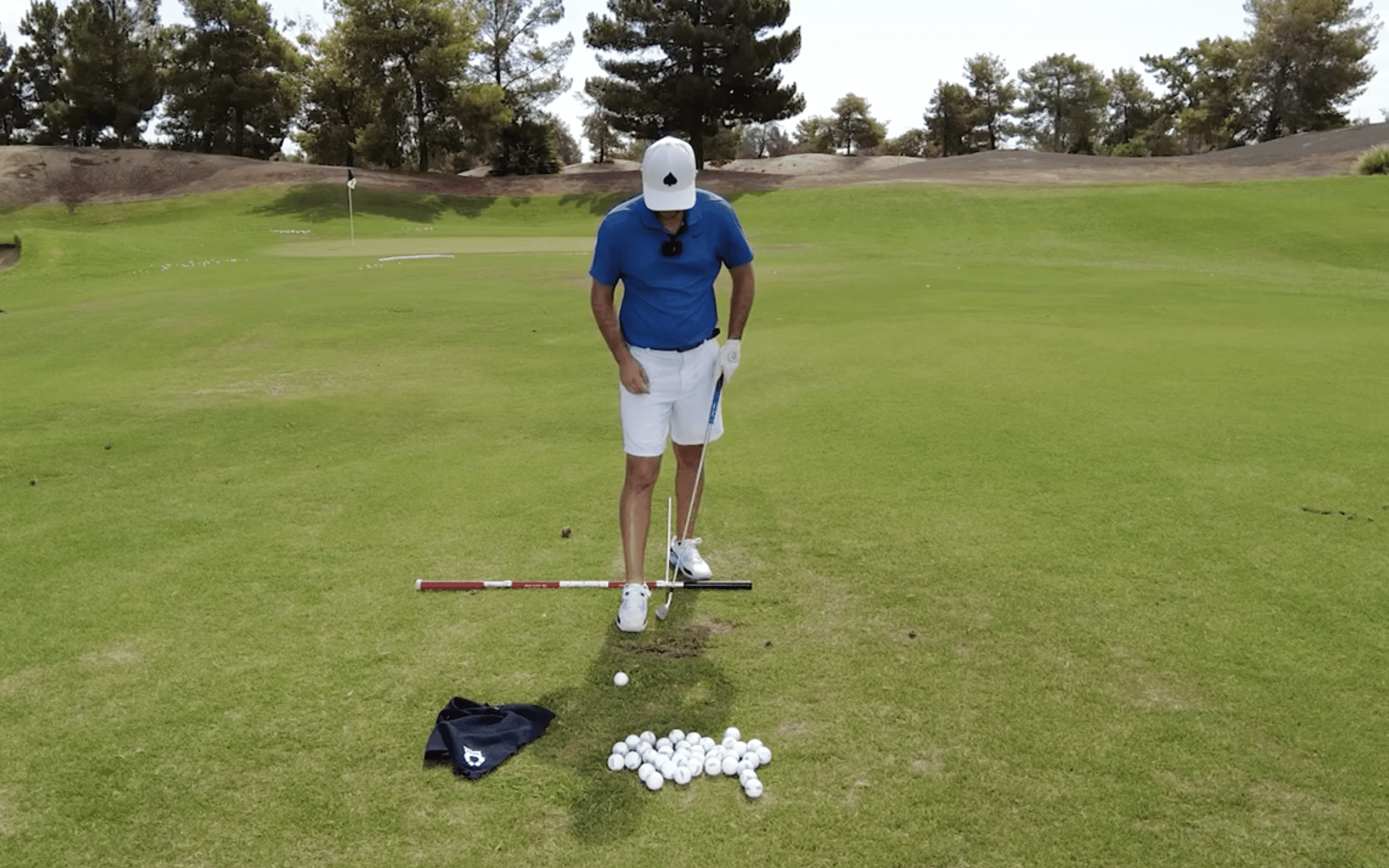 Golfer practicing on the course with golf balls.