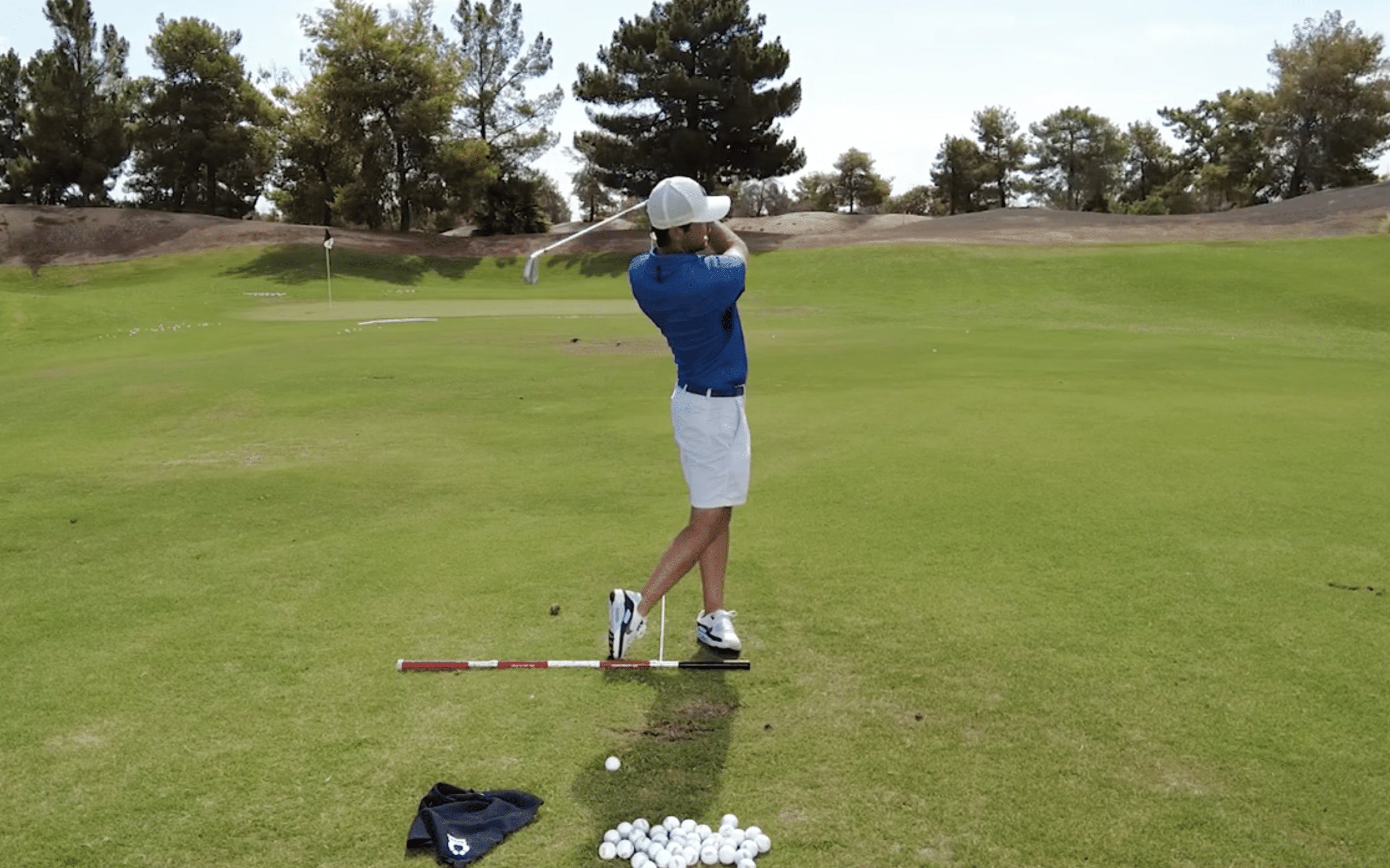 Golfer practicing swing on a golf course.