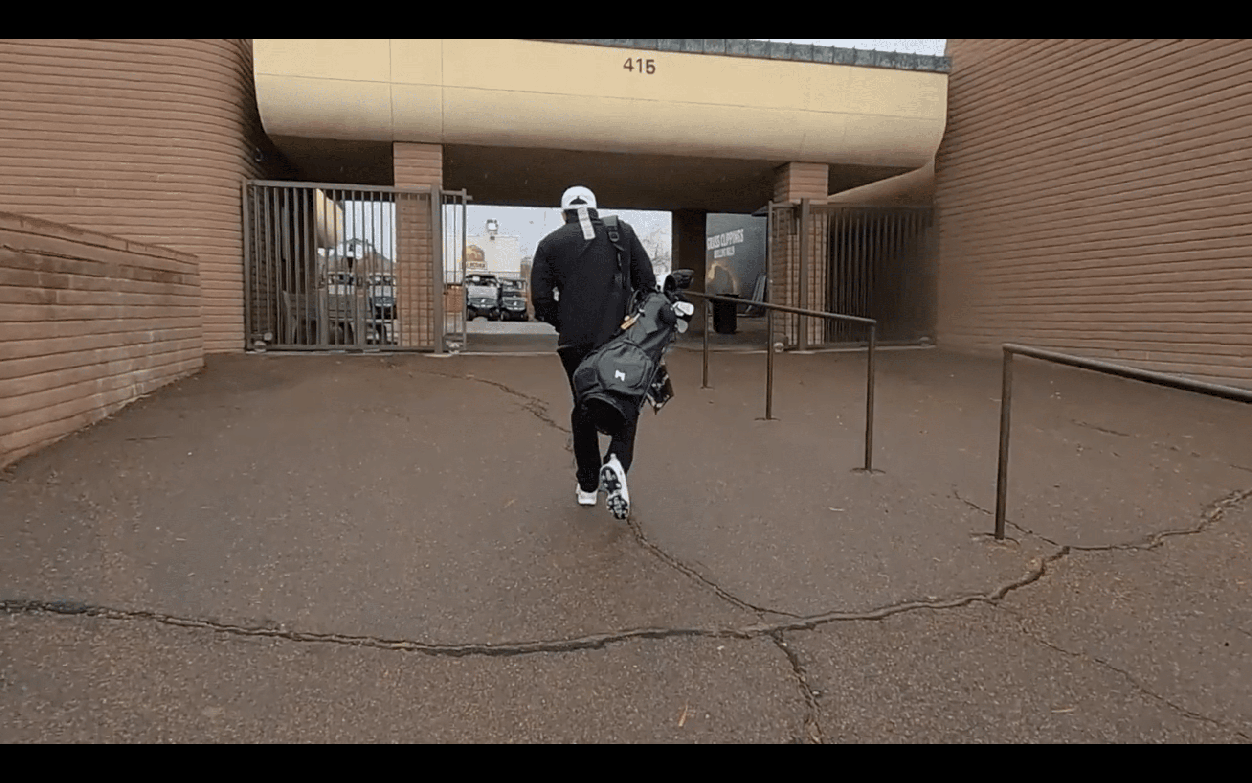 Person walking towards entrance carrying golf bag.