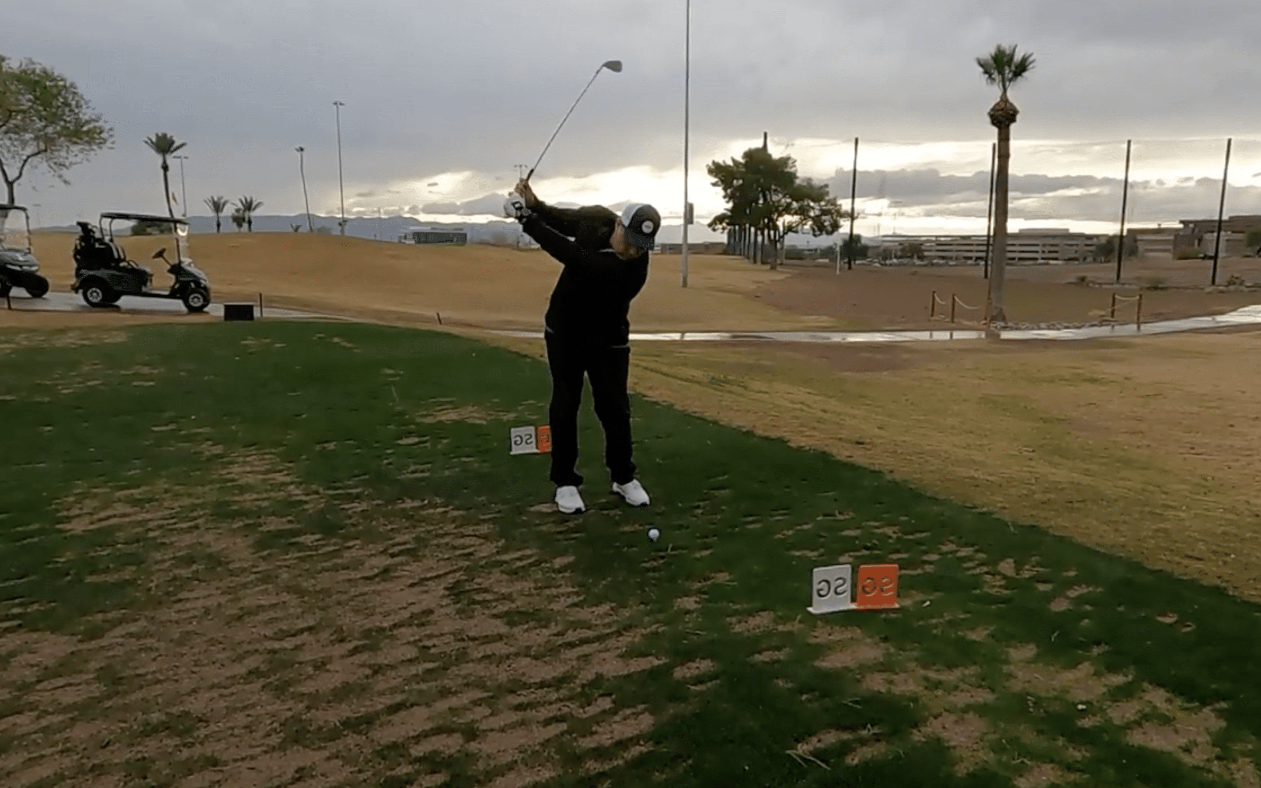 Golfer preparing to swing on a driving range.