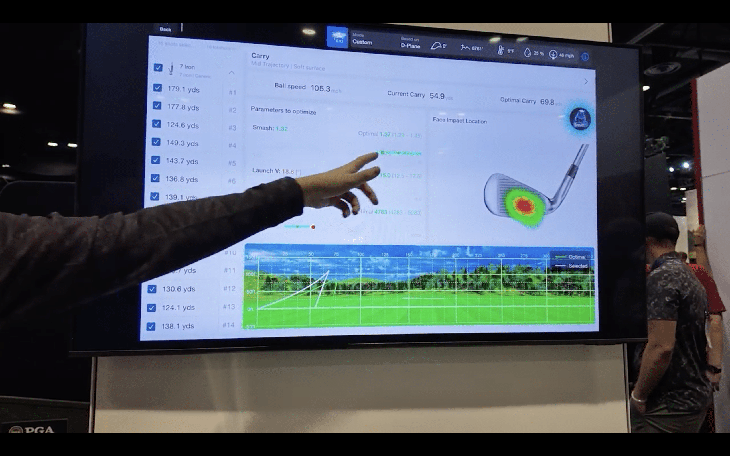 Golfer analyzing swing data on screen.