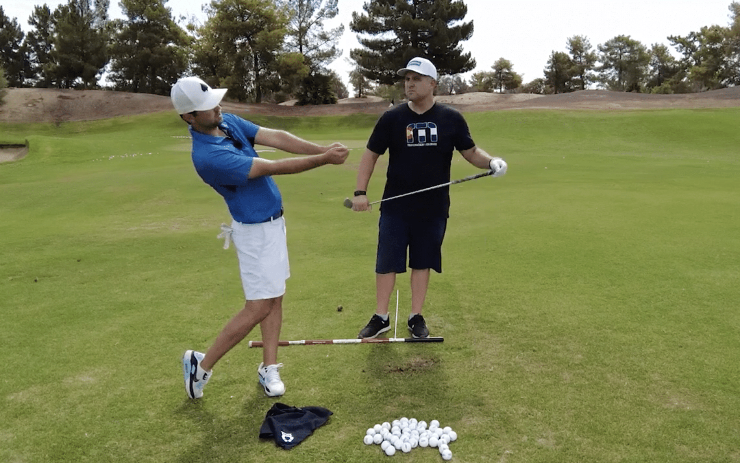 Two golfers practicing swings on the course.