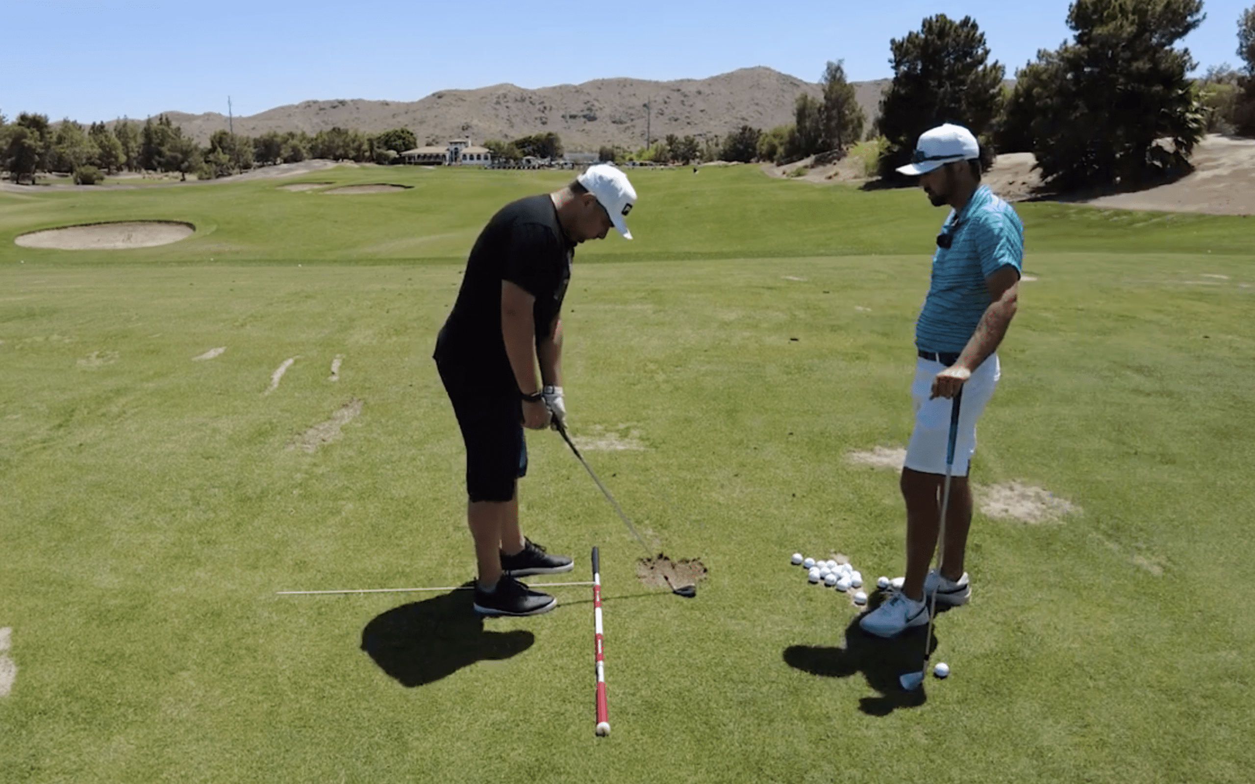 Two men practicing golf on a sunny day.