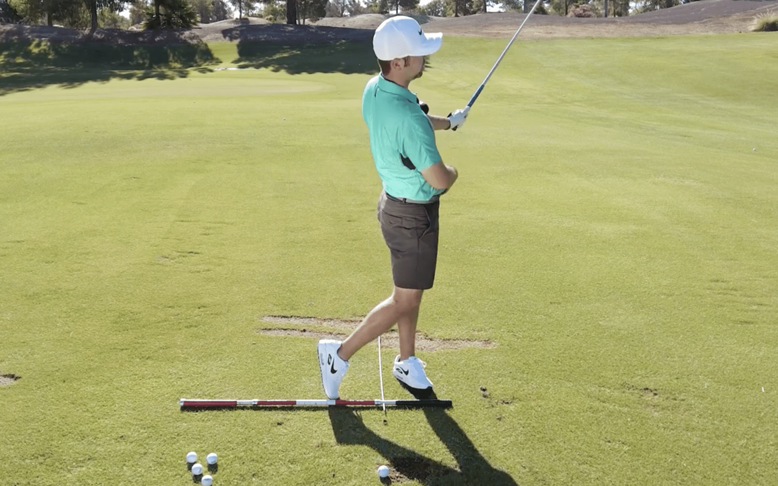 Golfer practicing swing on green field.