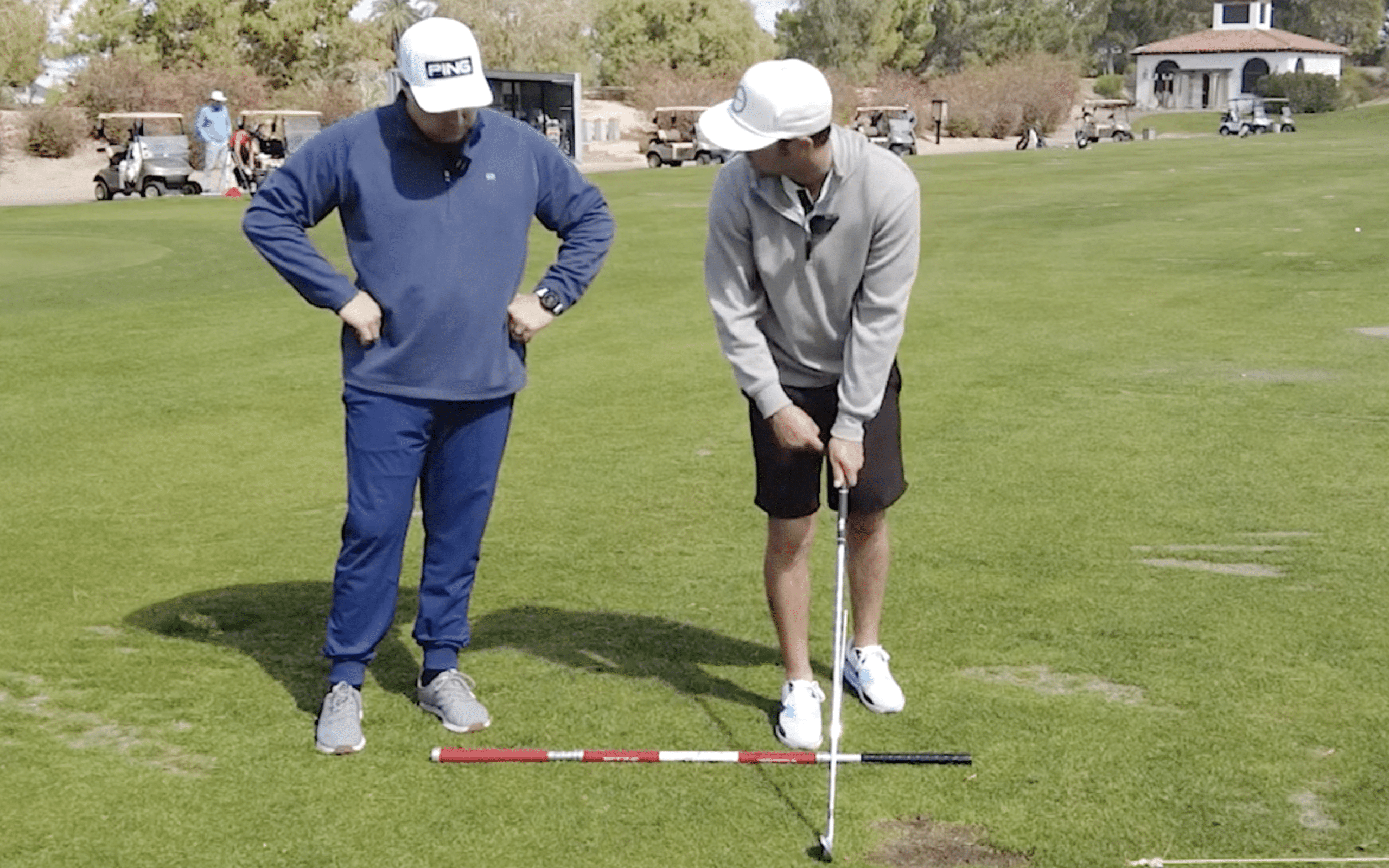 Two golfers practicing on a putting green.