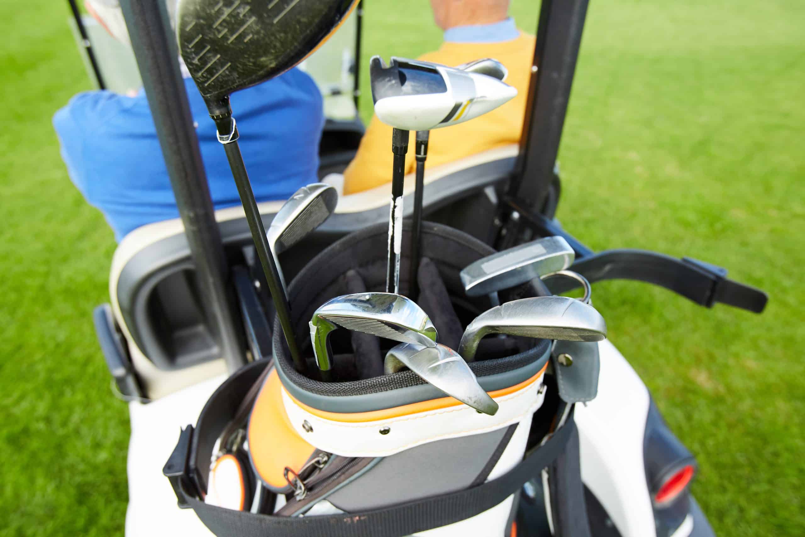 Golf clubs in a cart on the grass.