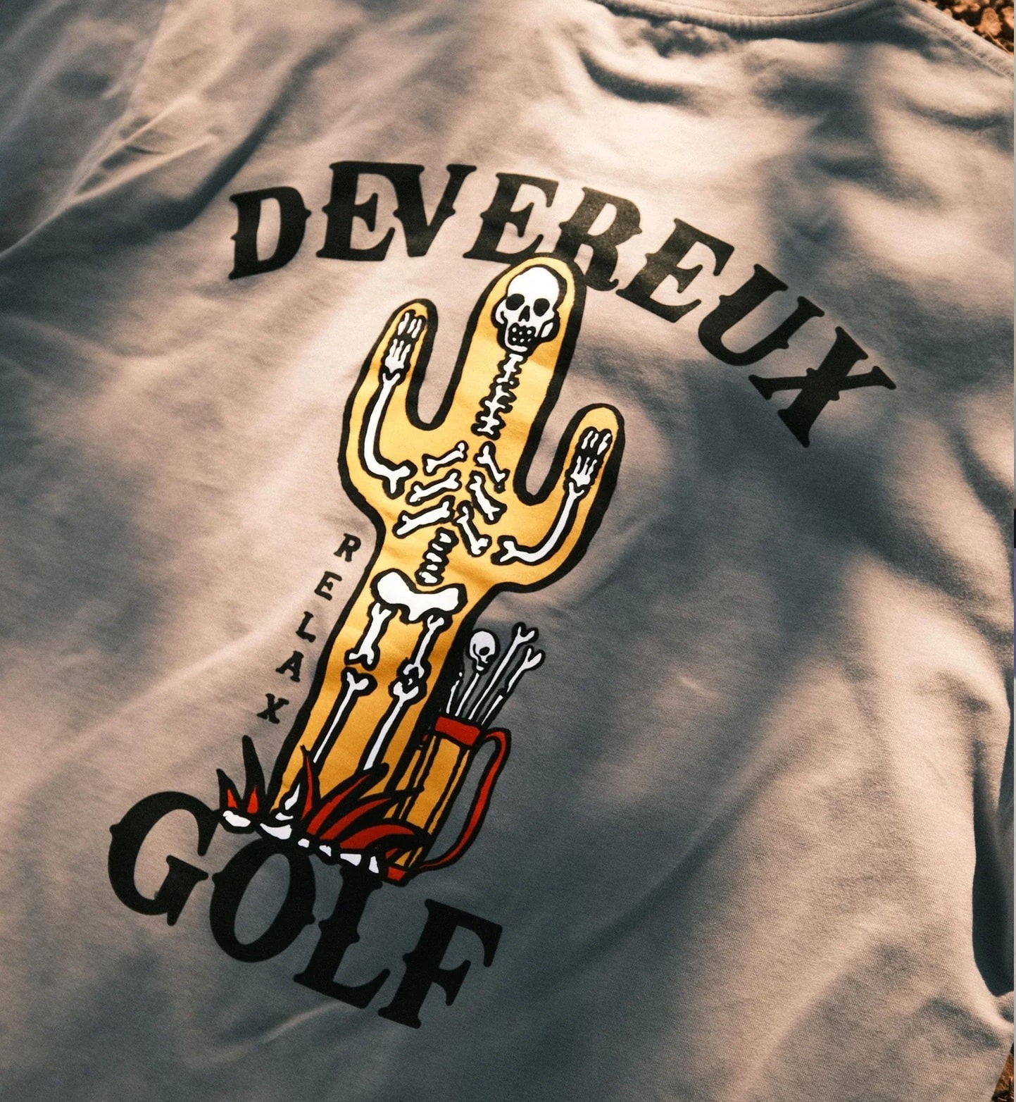 Graphic tee featuring skeleton cactus and golf theme.