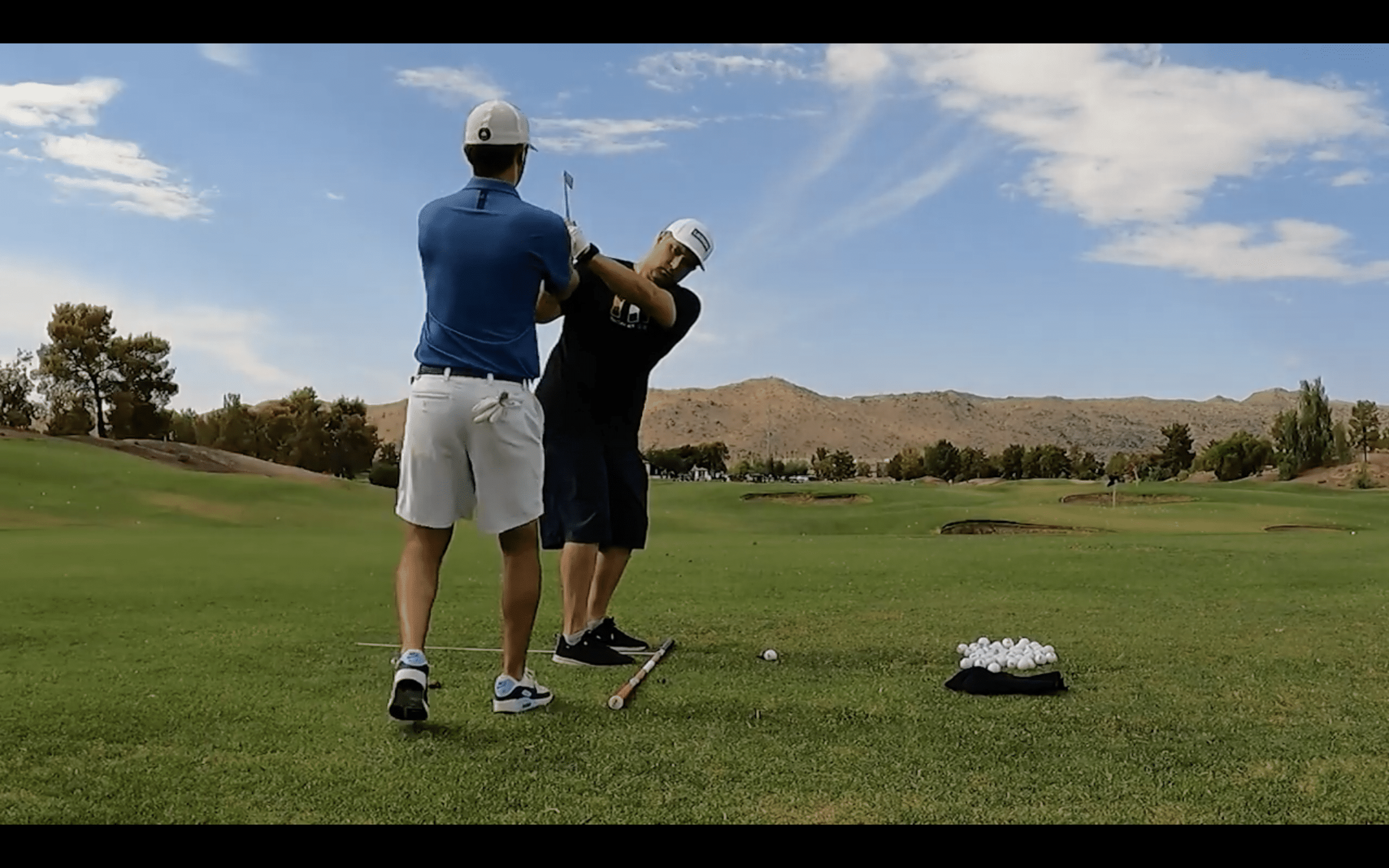 Two golfers practicing swings on a sunny day.