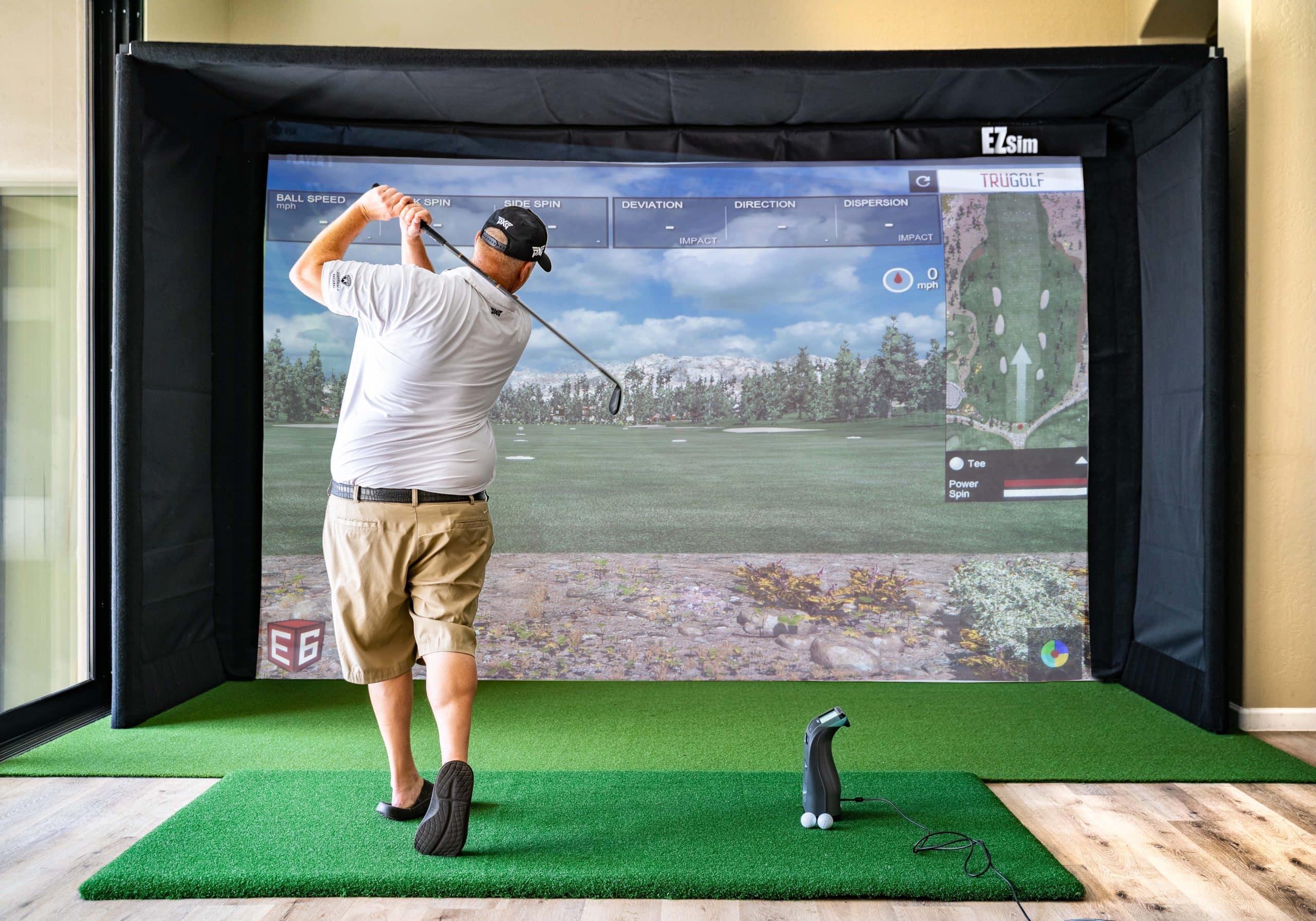 Man playing golf on indoor simulator screen