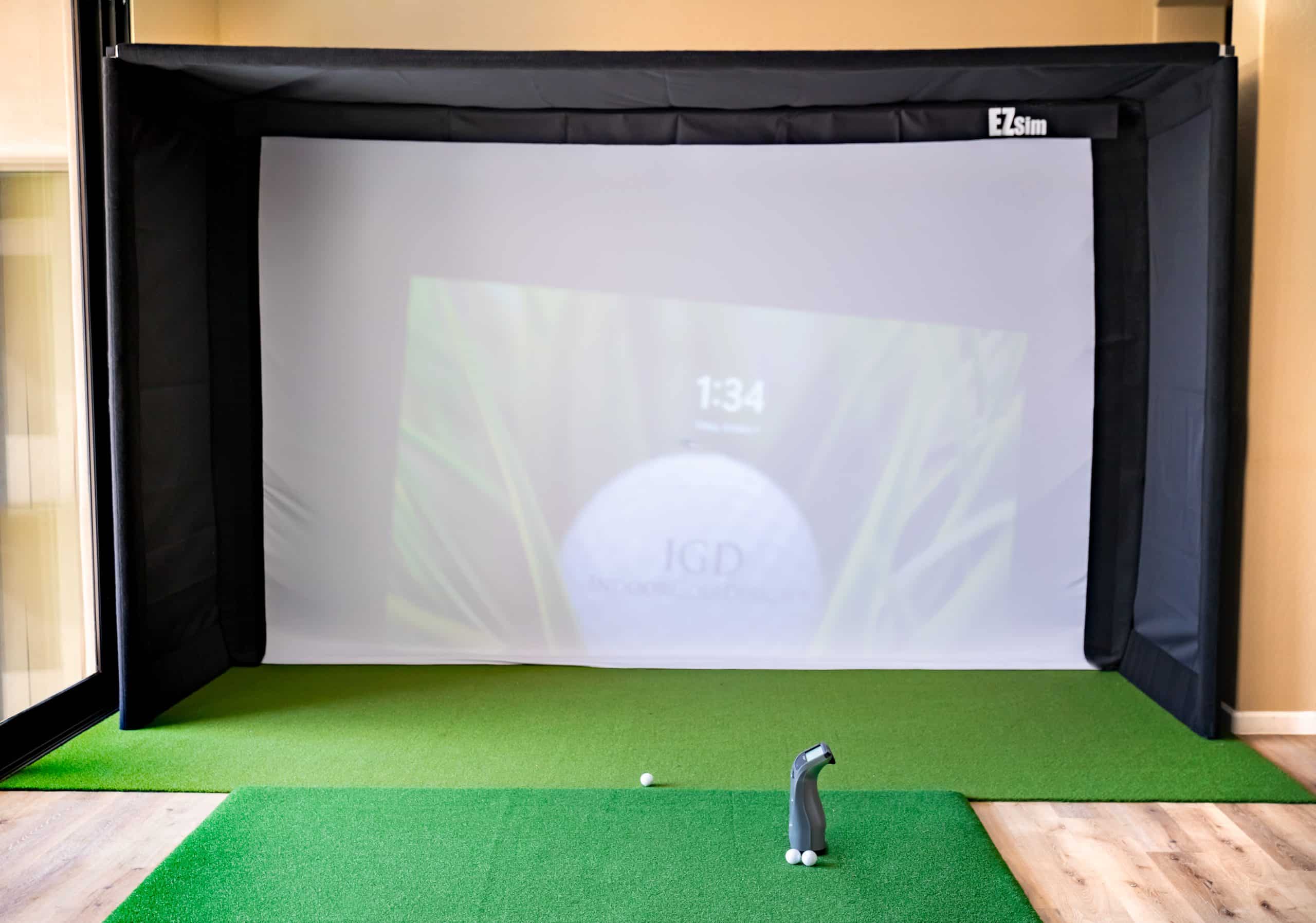 Indoor golf simulator with green turf setup