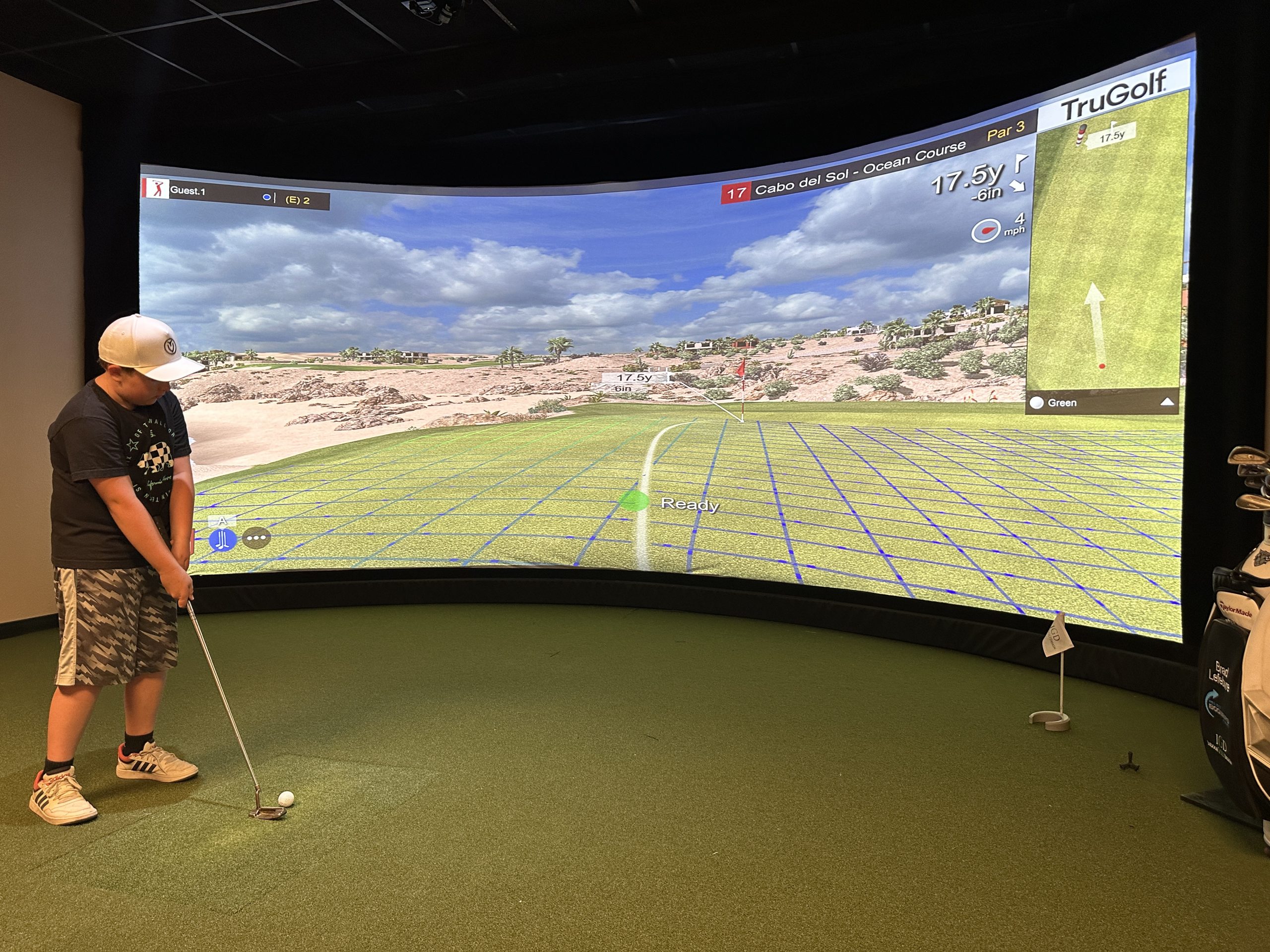 Child practicing golf on indoor simulator screen