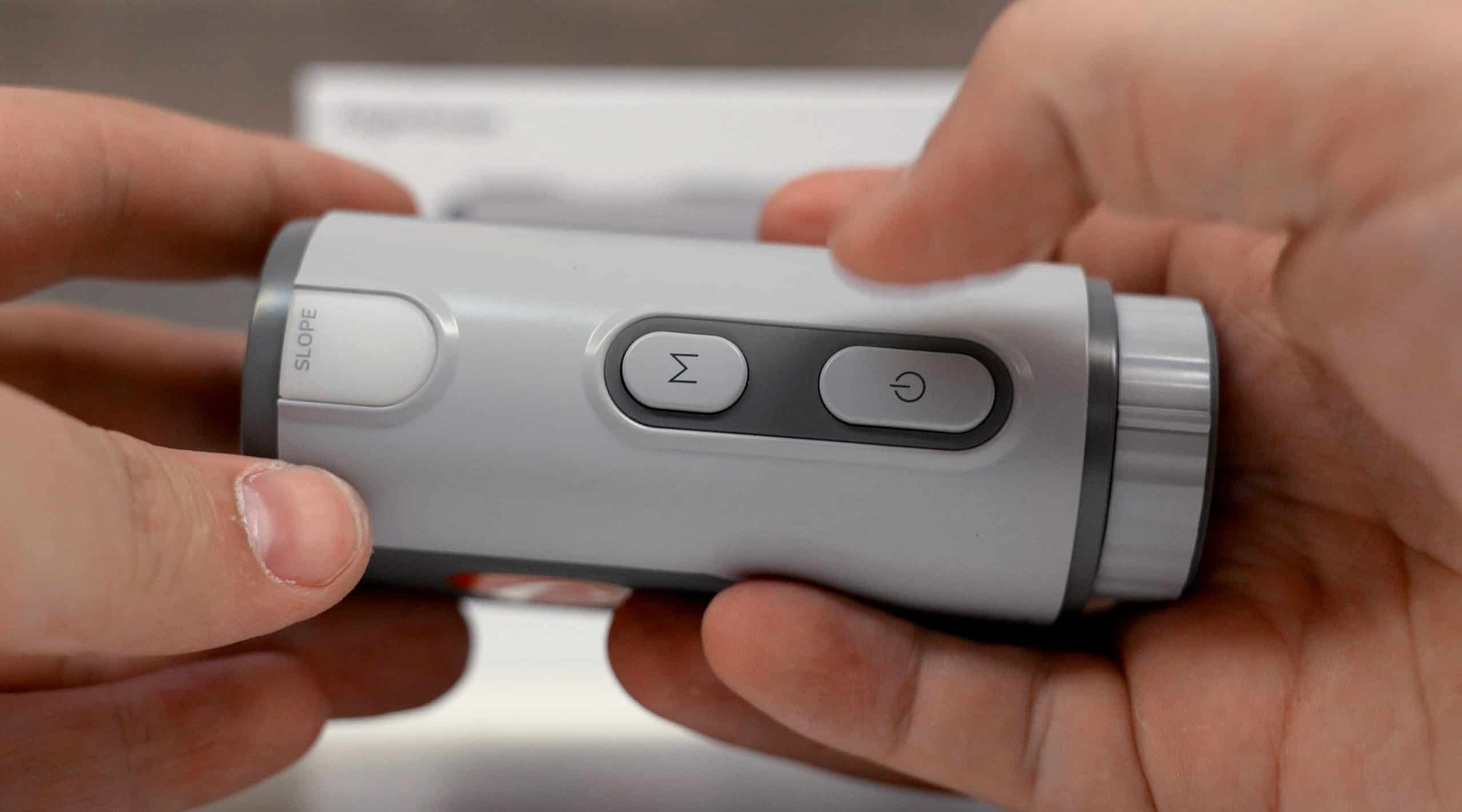 Person holding gray golf rangefinder with buttons
