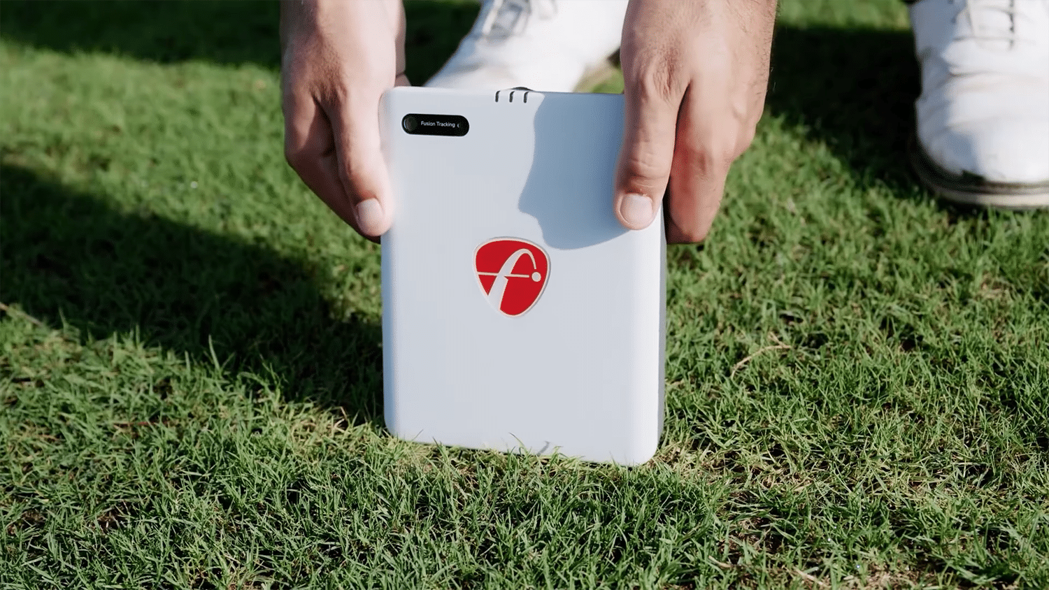 Person placing golf launch monitor on grass