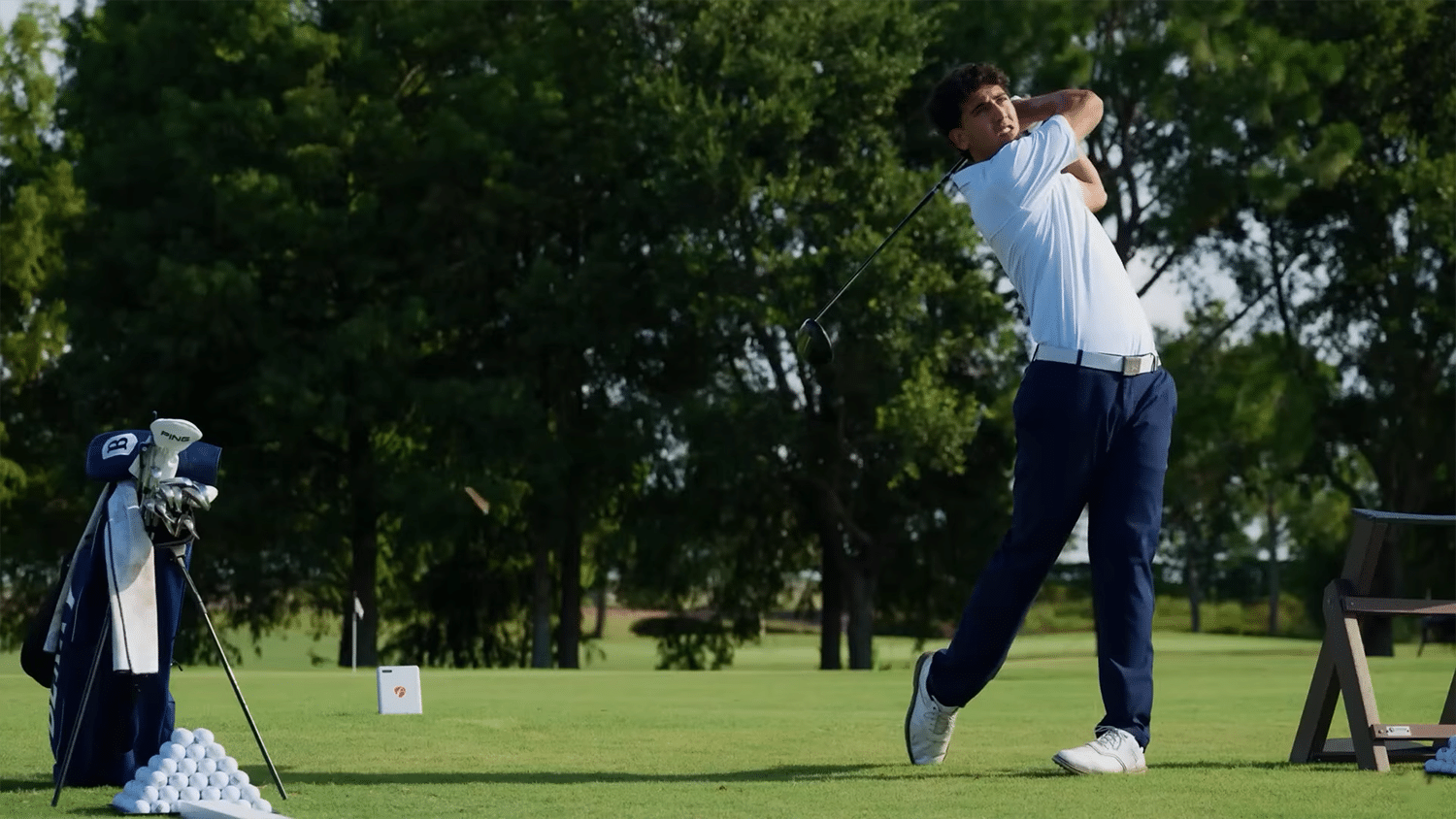Golfer swinging club on lush green course