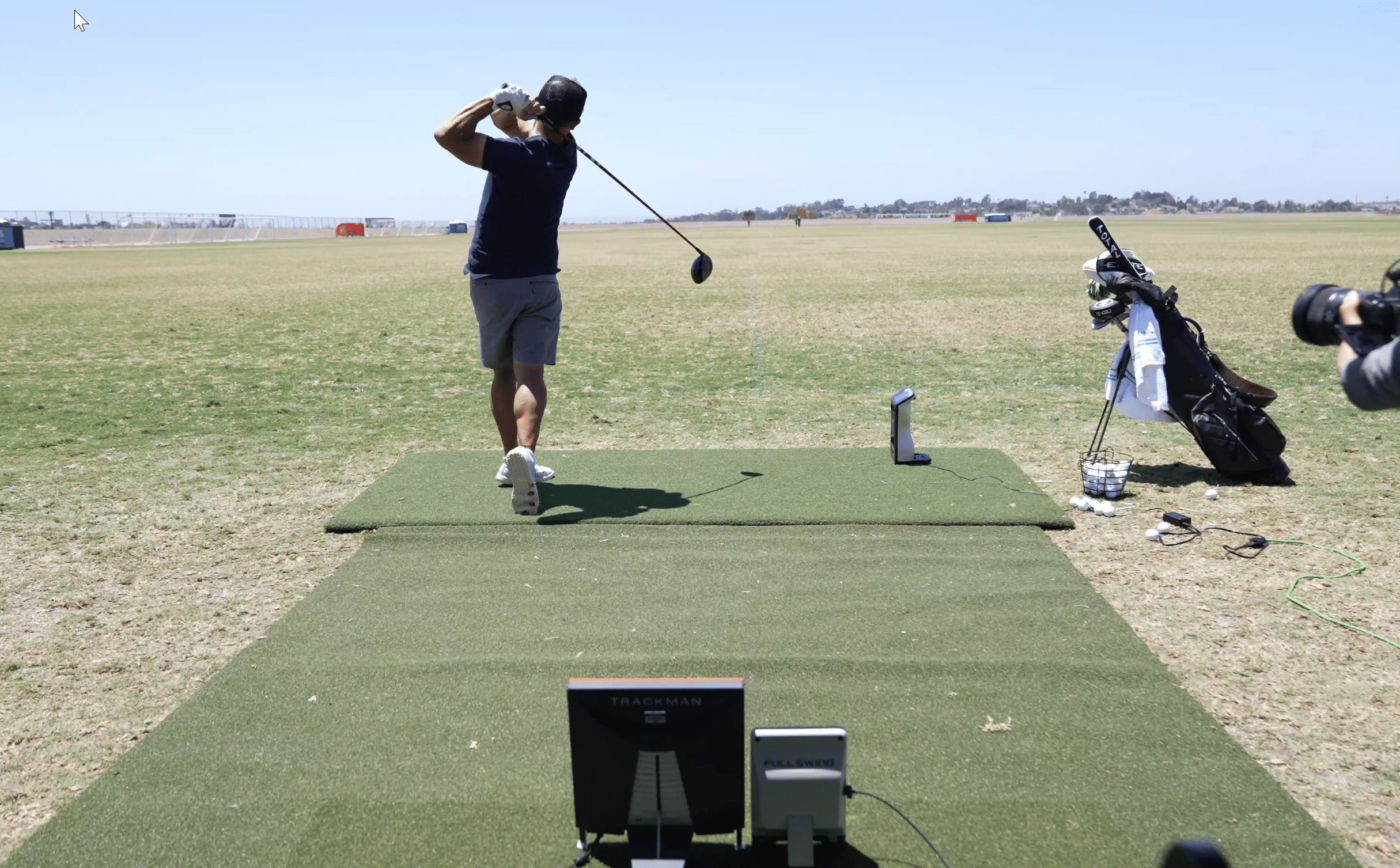 Golfer swinging driver at outdoor practice range