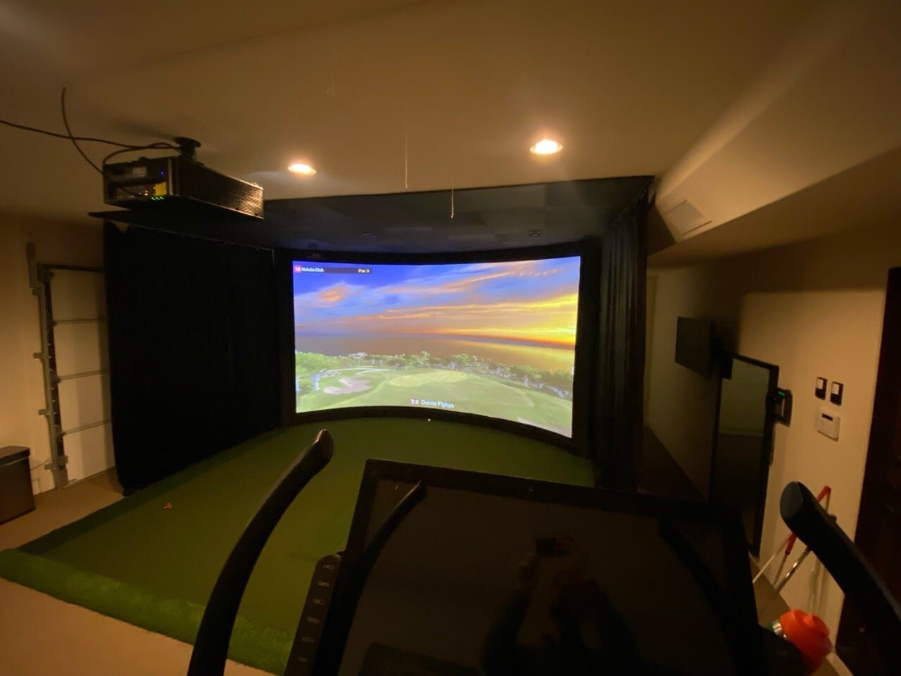 Indoor golf simulator setup with projector screen
