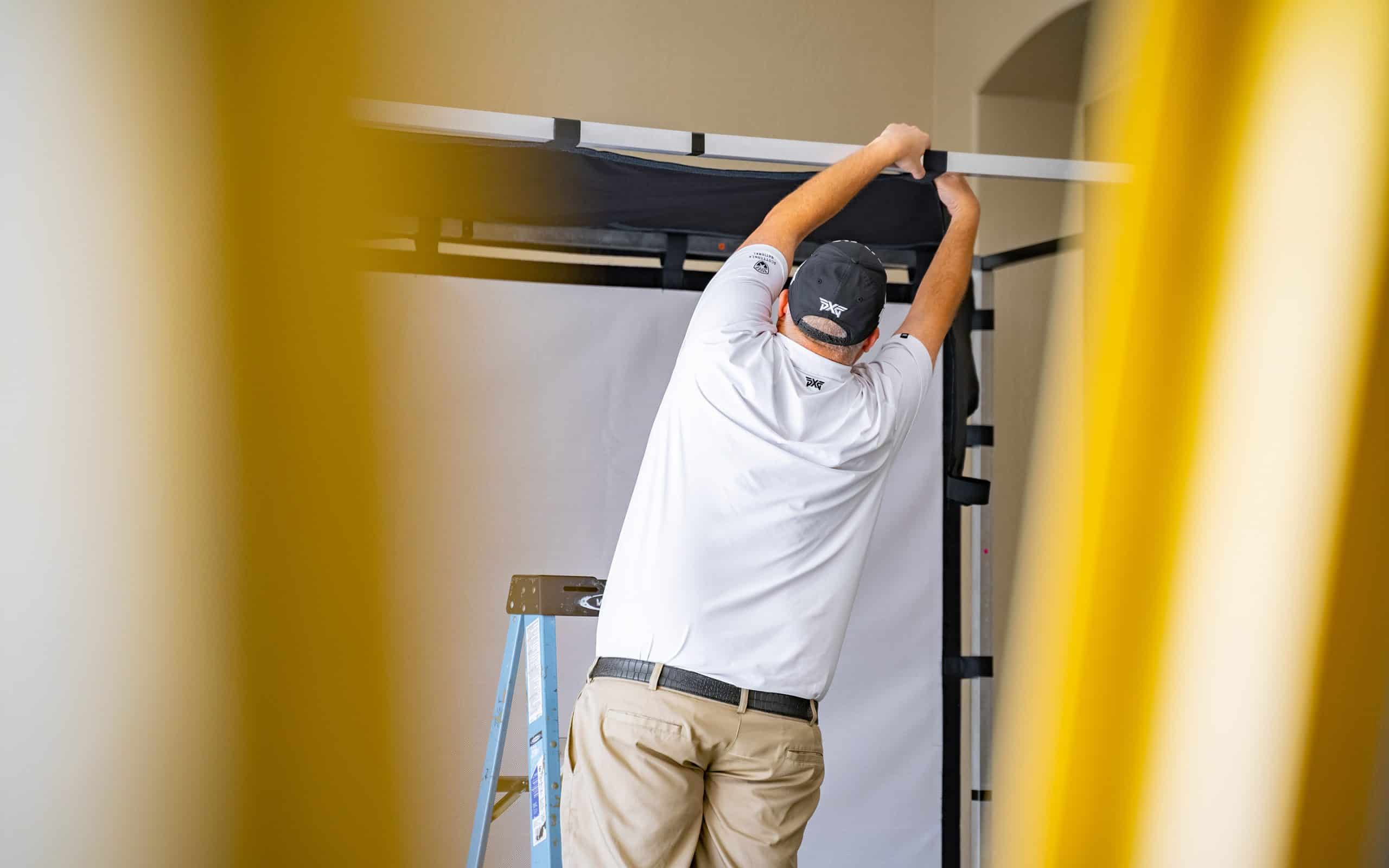 Man adjusting frame while standing on ladder