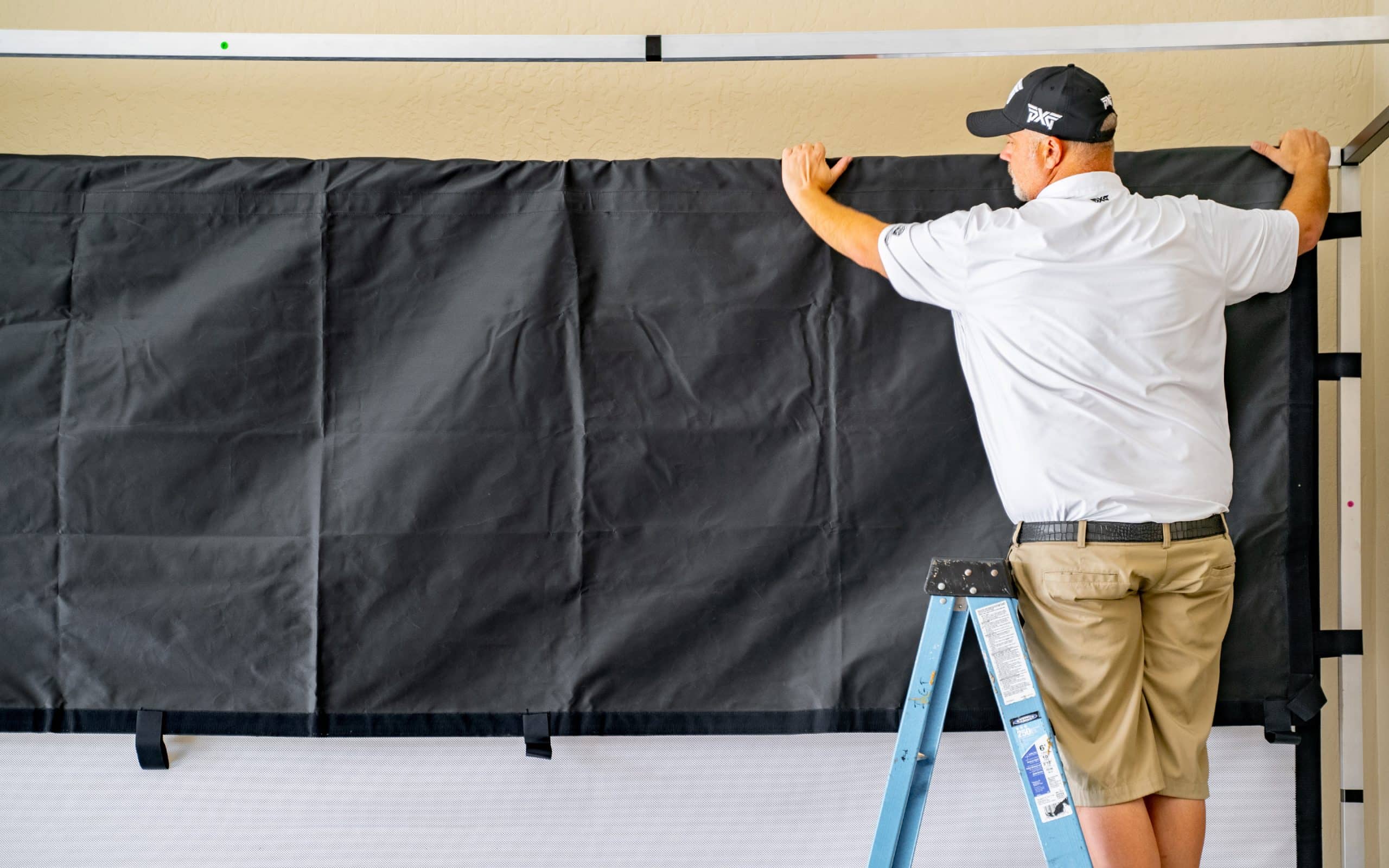 Man on ladder hanging black curtain