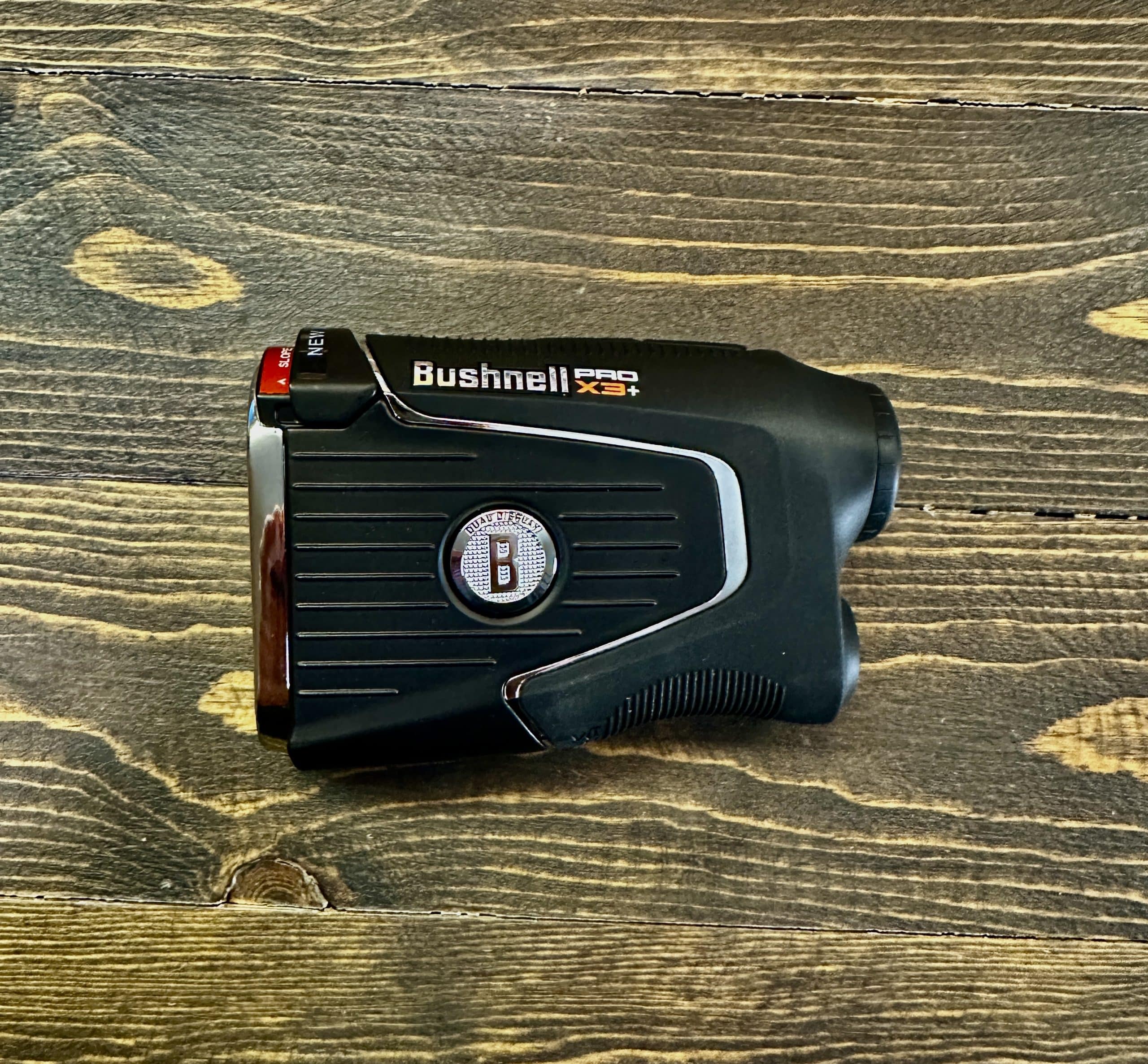 Bushnell Pro X3+ golf rangefinder on wooden surface