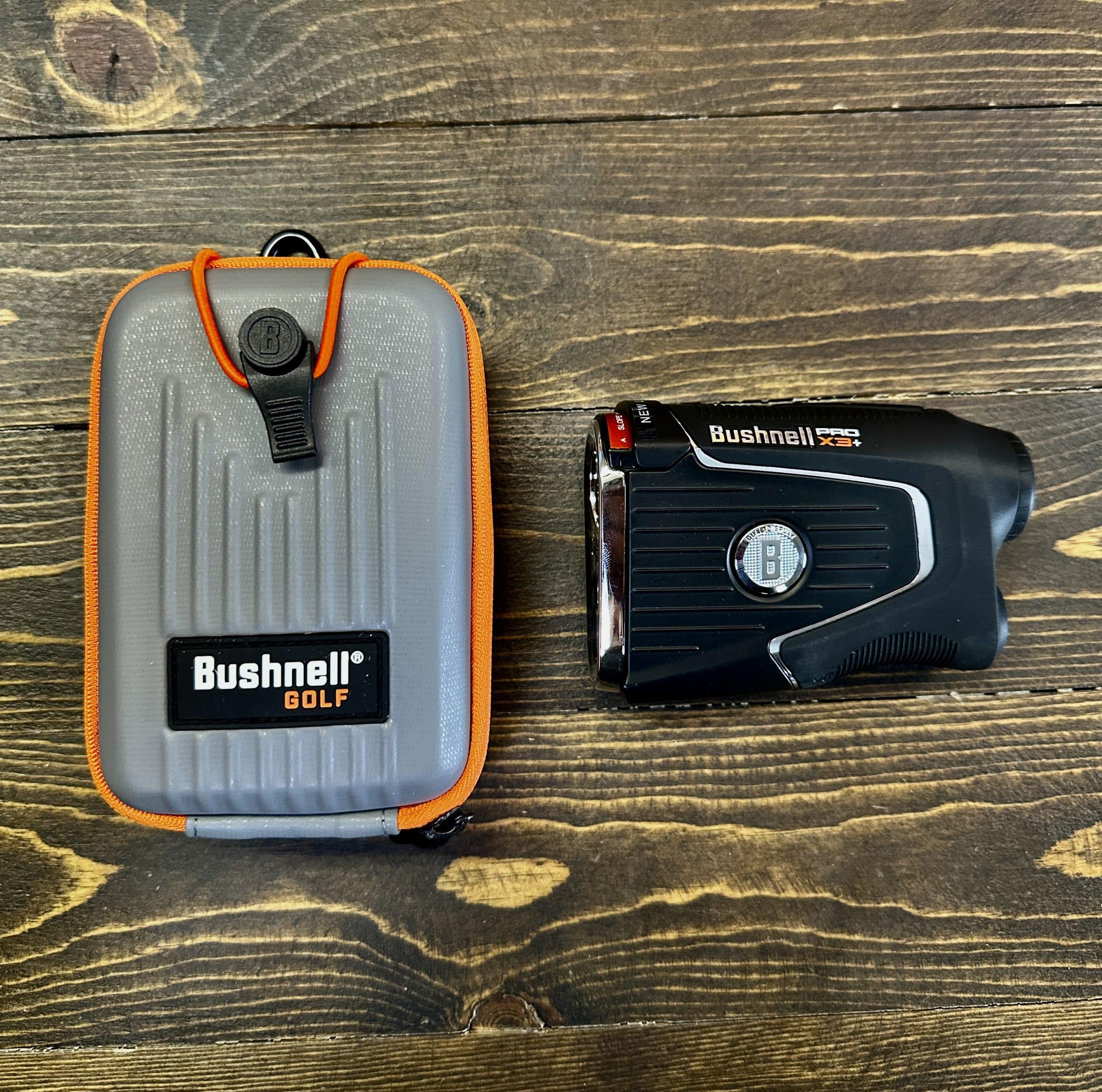 Bushnell golf rangefinder with protective case on wood