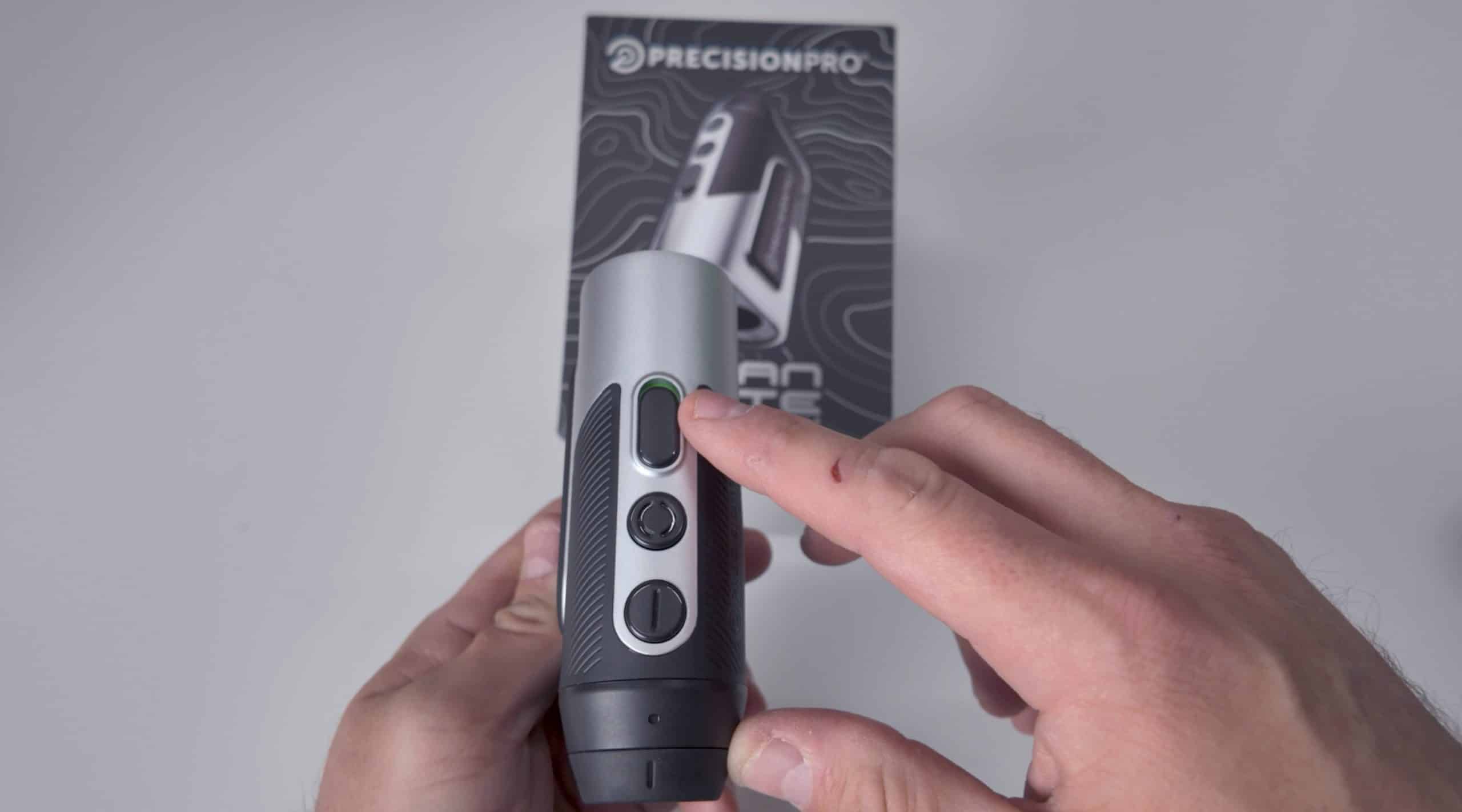 Person pressing button on golf rangefinder device