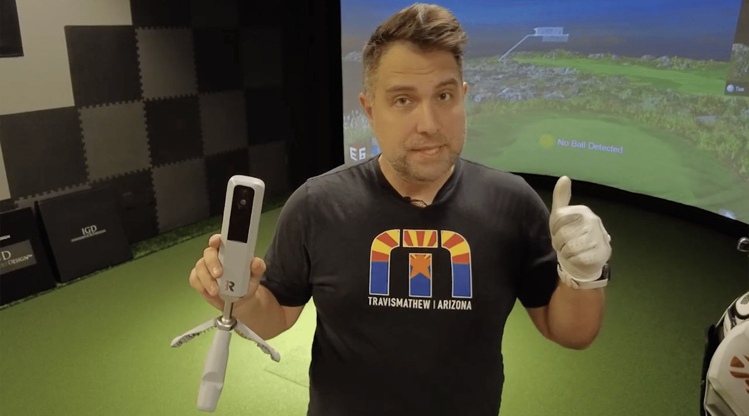Man demonstrating golf simulator with launch monitor device