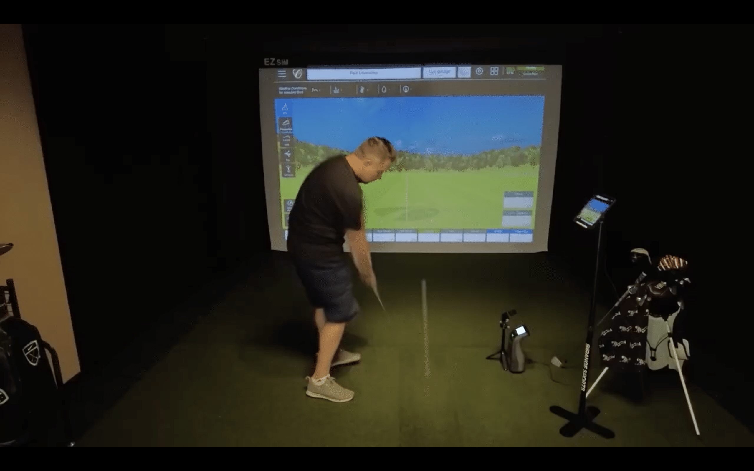 Man playing golf on indoor simulator screen