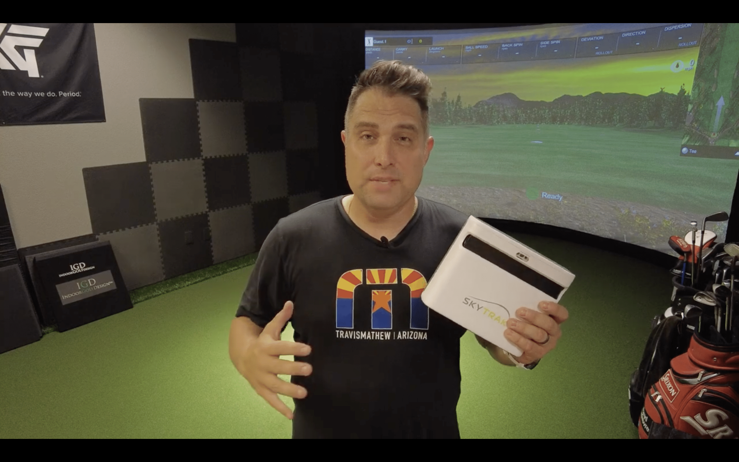 Man holding SkyTrak golf launch monitor indoors