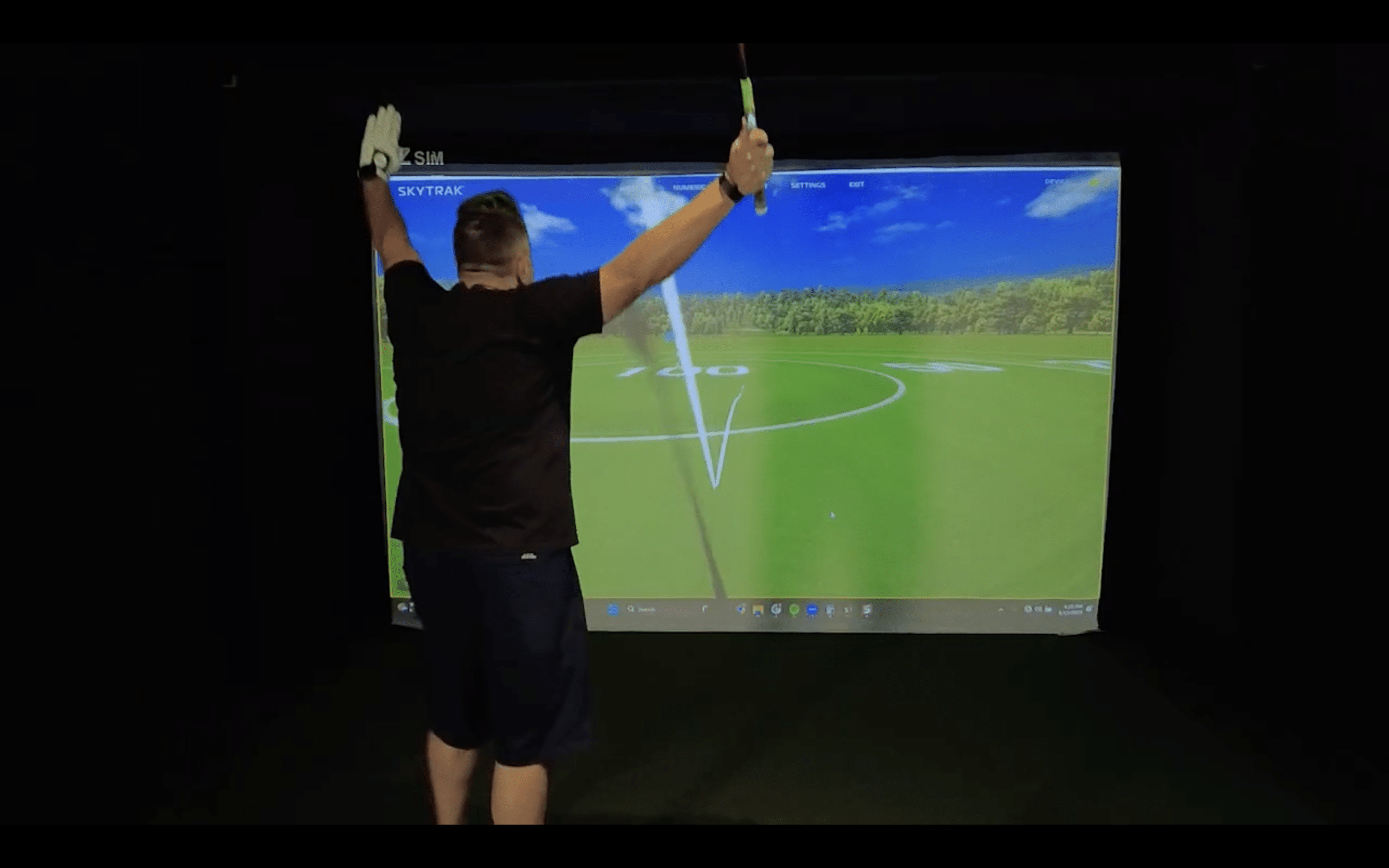 Golfer celebrates shot on indoor golf simulator