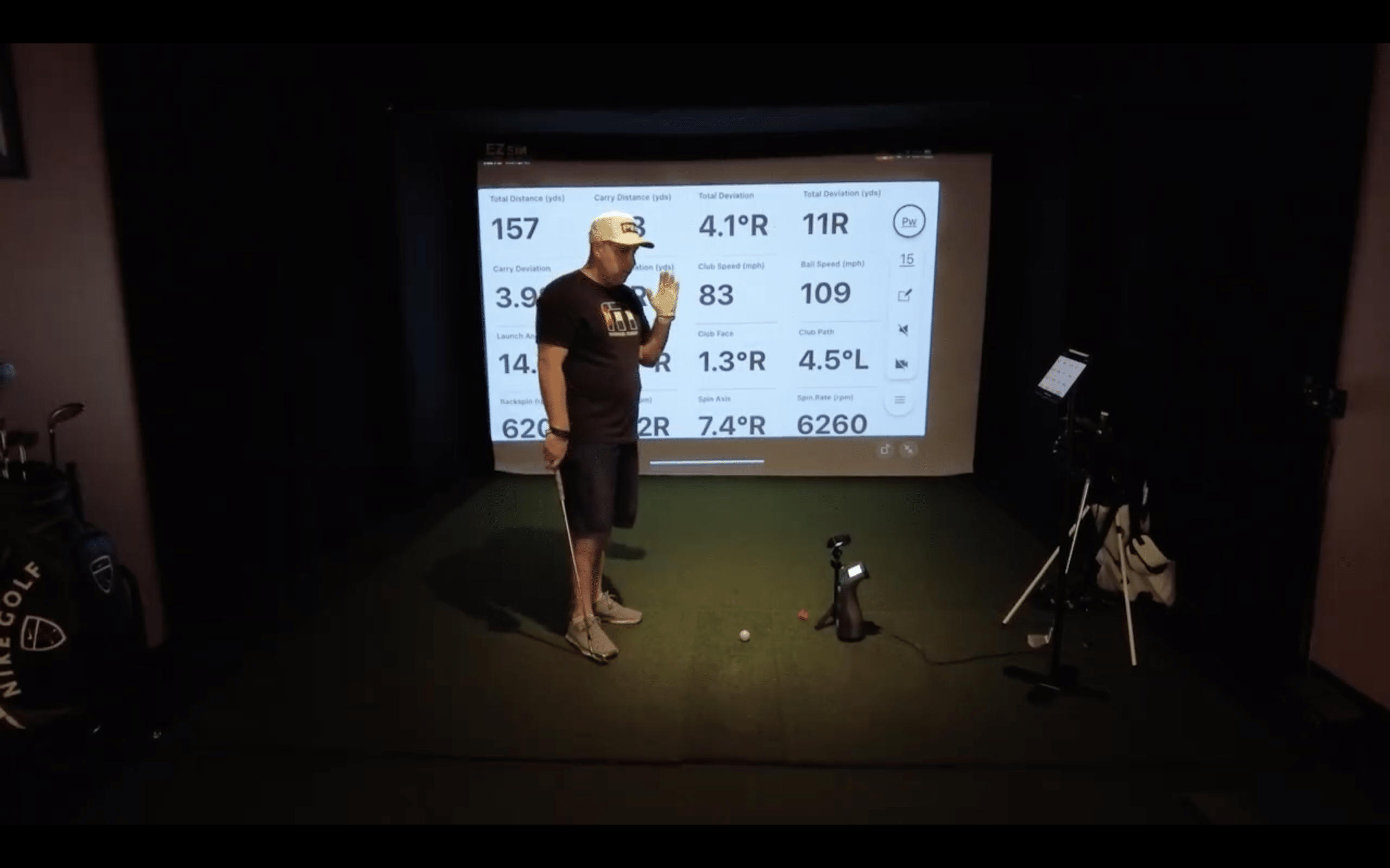 Golfer analyzing data on indoor golf simulator screen.