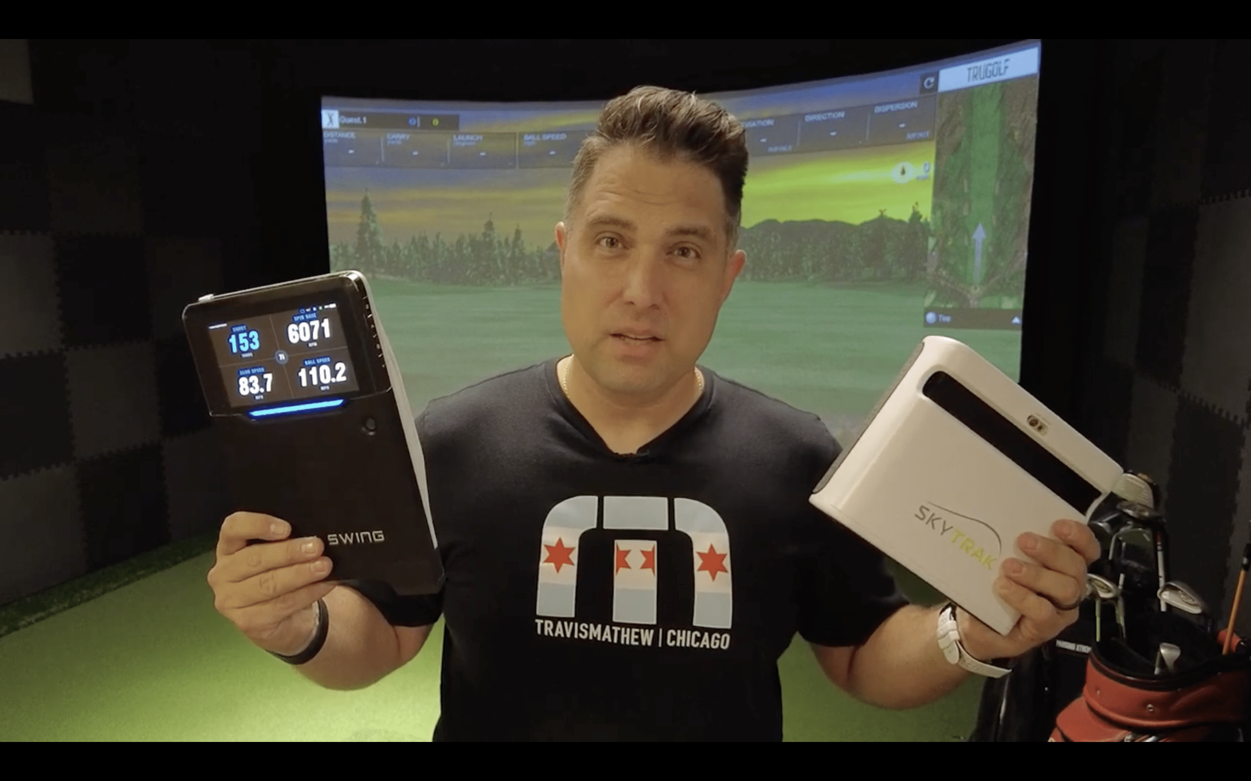Man comparing two golf launch monitor devices indoors