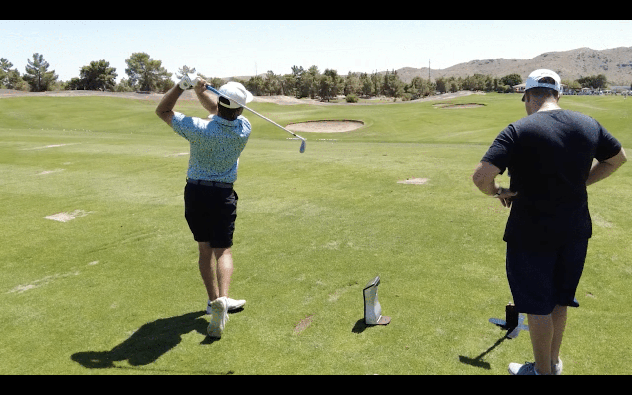 Two men playing golf on sunny course