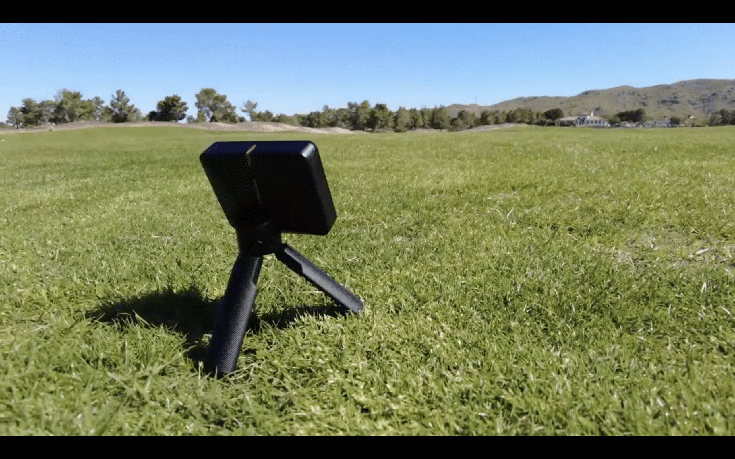 Portable camera on tripod in grassy field