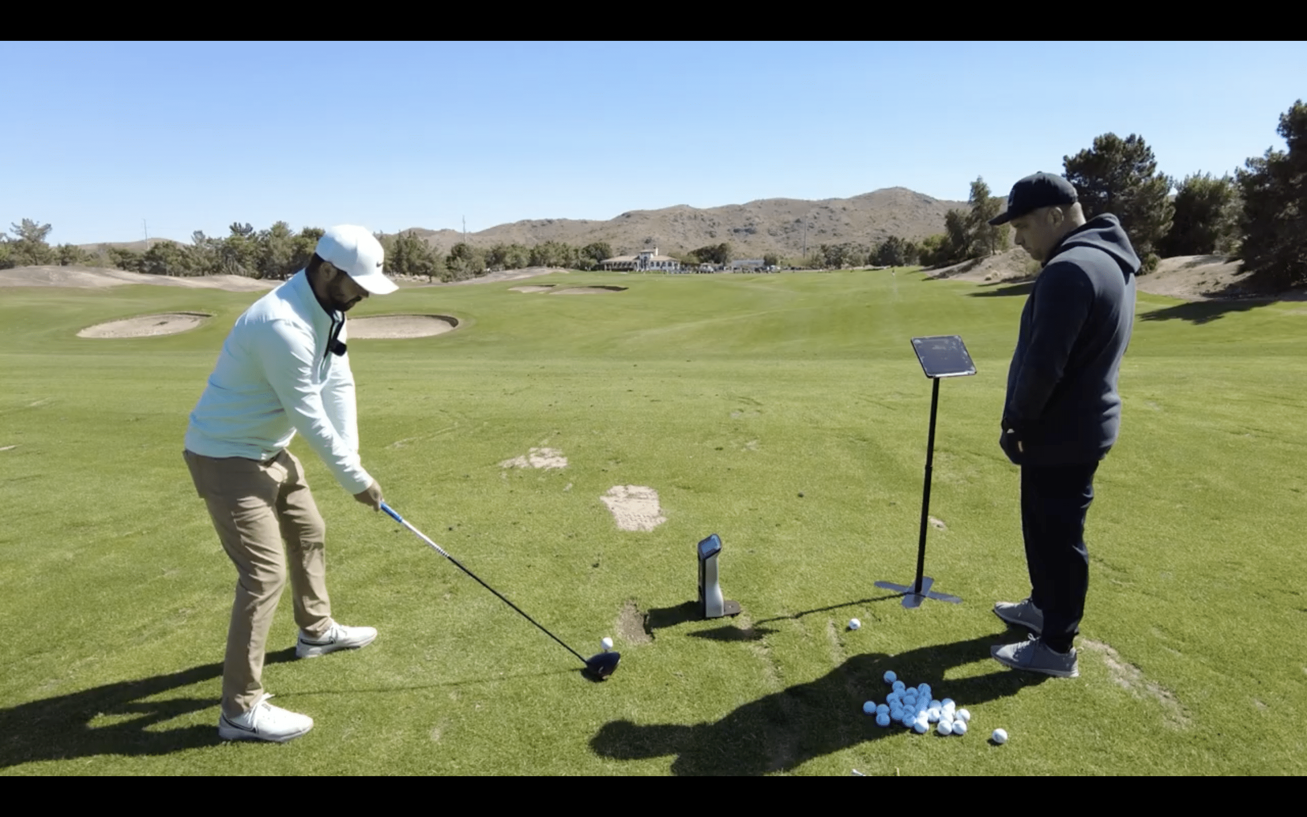 Golfer practicing swing with coach on driving range